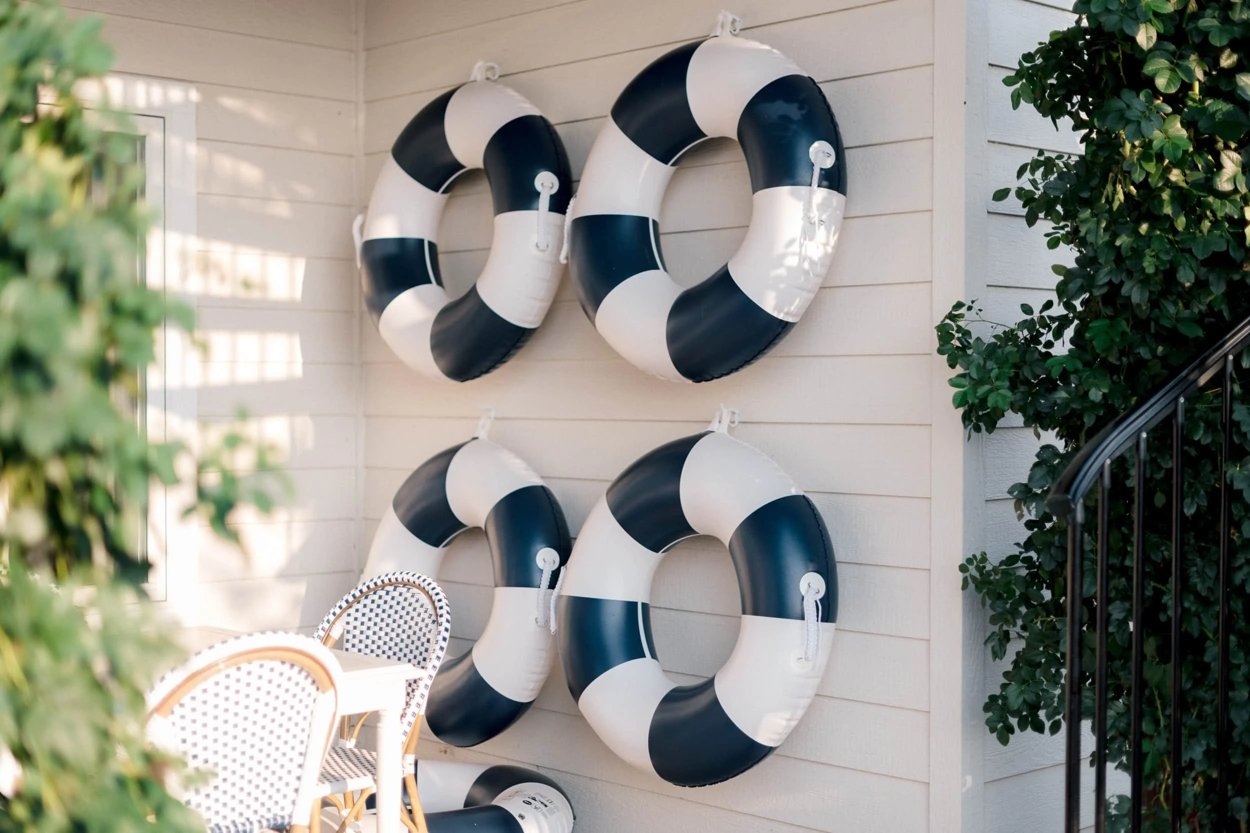 Wall decor on an outdoor patio featuring six navy and white life preservers arranged above the seating area.