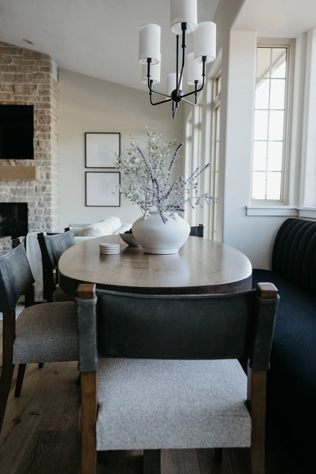 Close-up of the dining seating showing a gray fabric upholstered chair with a dark leather back strap, set in the dining nook.