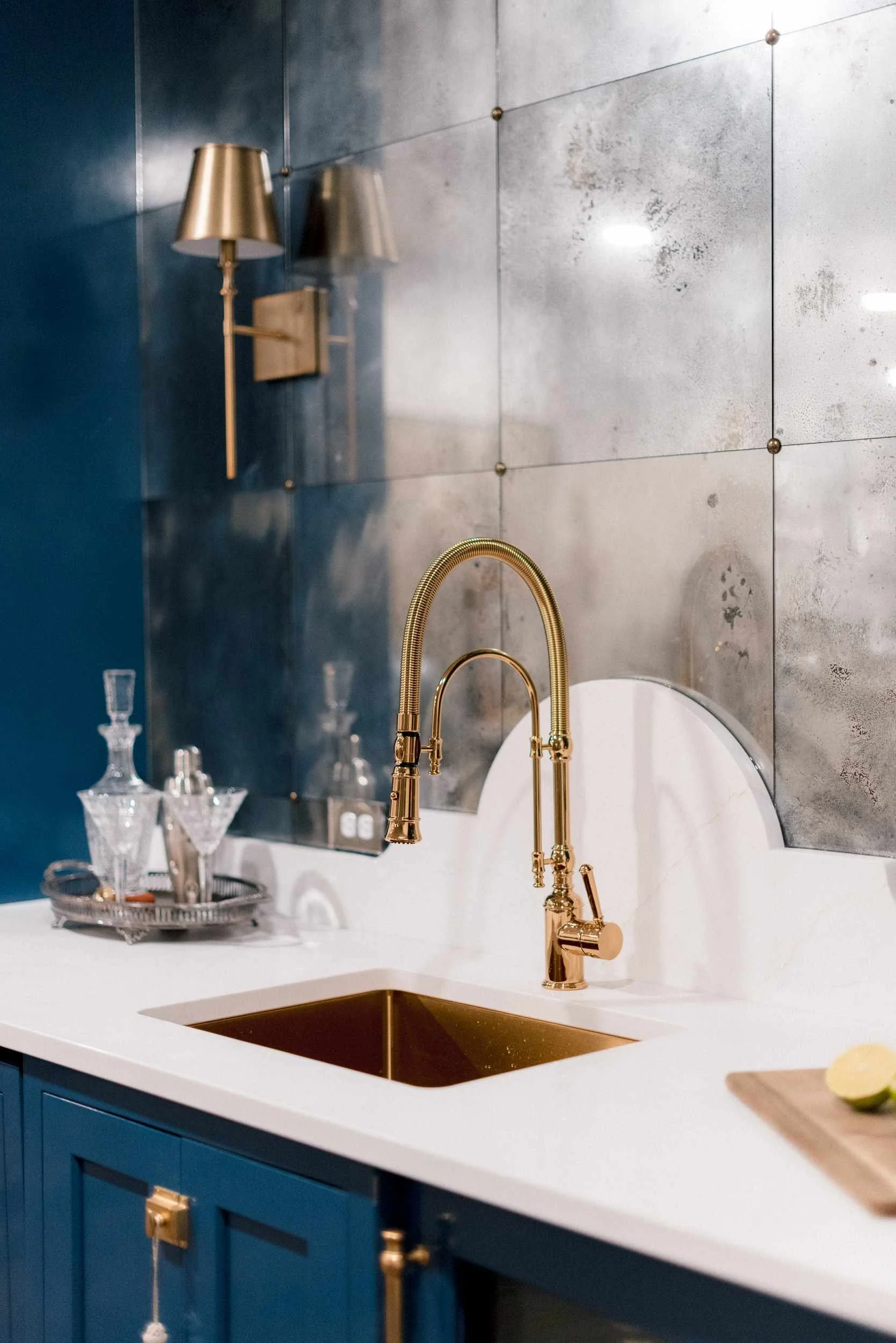 Detail of the gold gooseneck faucet and square bronze sink set into the white quartz countertop, with a crystal decanter nearby.