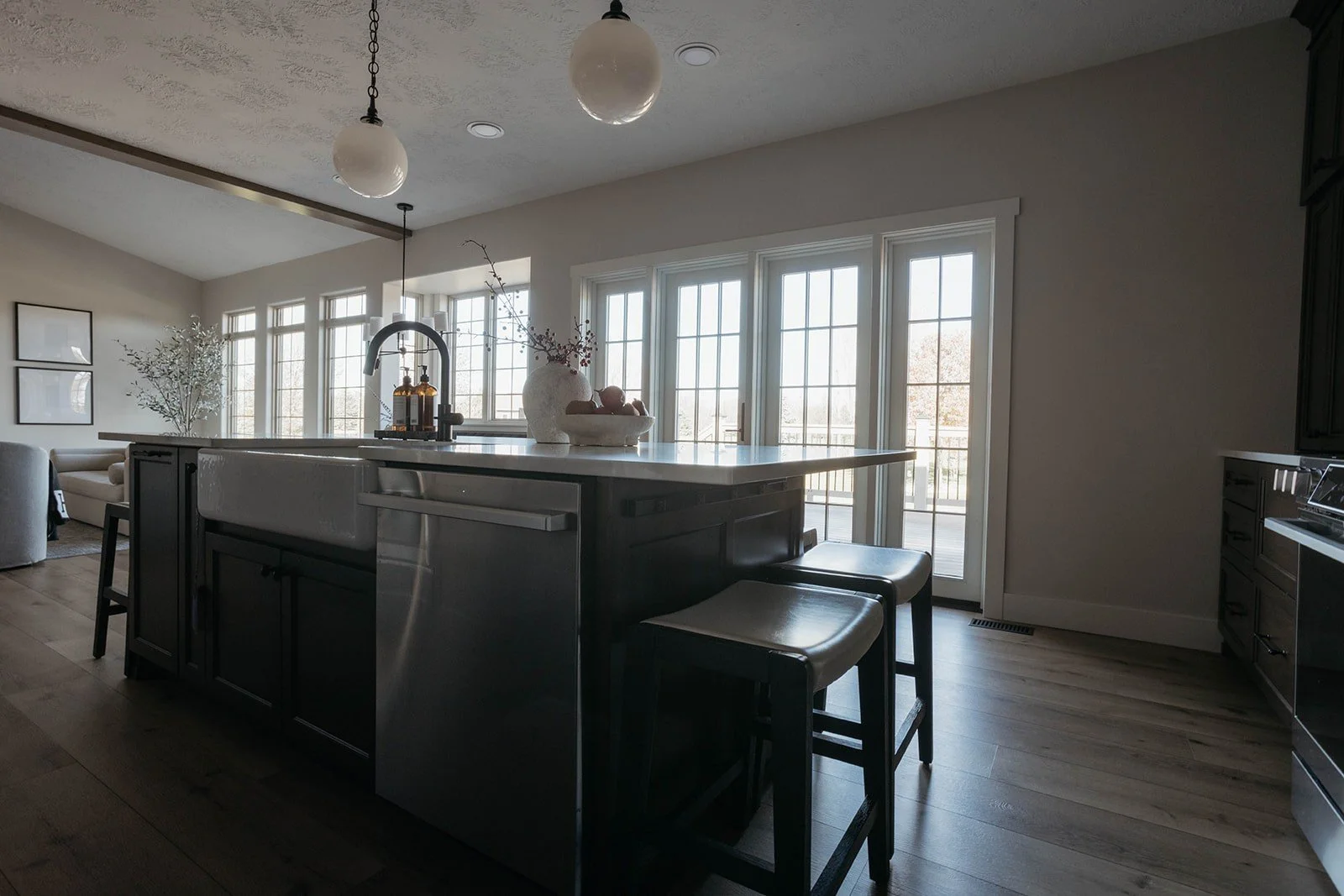 Wide view of the large kitchen island with a stainless steel base and a white counter, set against a backdrop of large windows and glass doors.