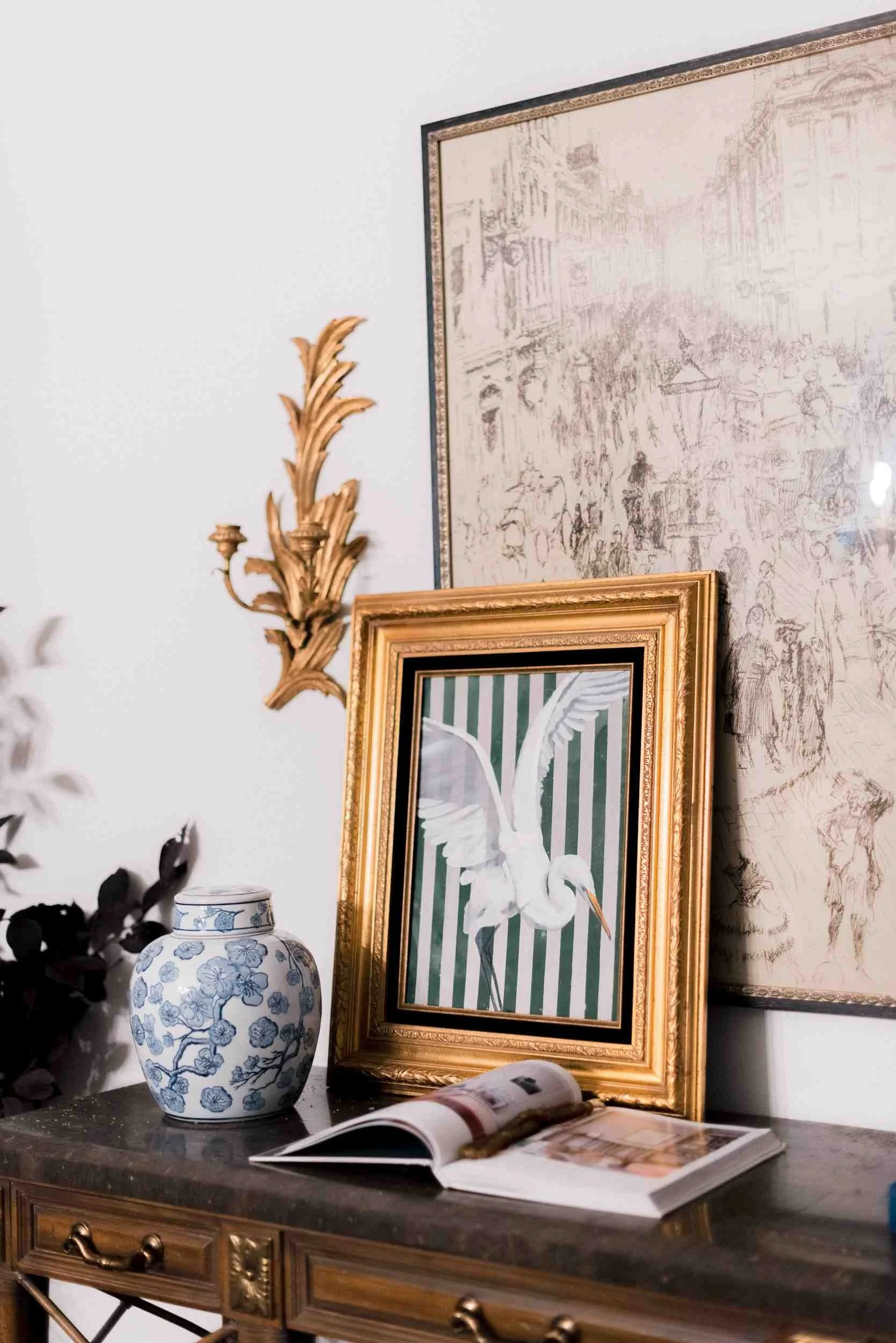Extreme close-up of the console styling, highlighting the original Christy Steen gold-framed painting of a white bird against green stripes, and the ginger jar.