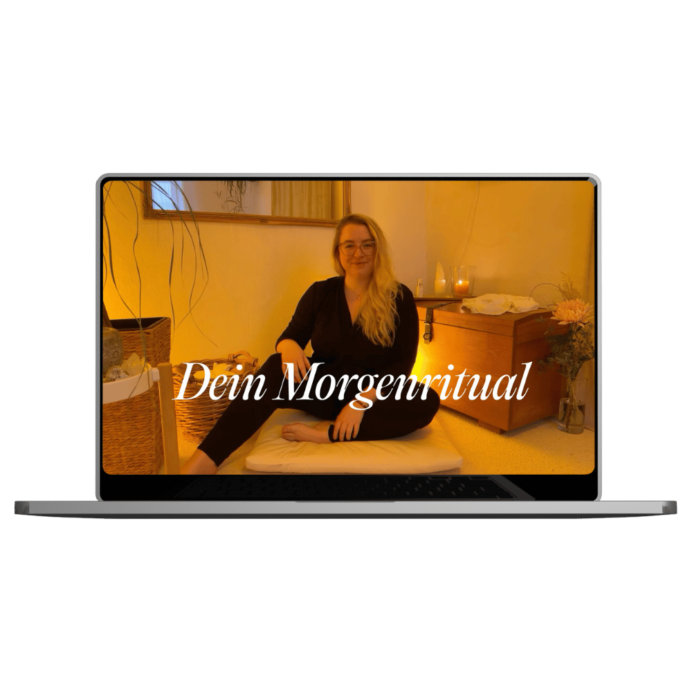 Ein Laptop zeigt eine Frau, die auf einem Kissen sitzend in einem gemütlichen Raum sitzt, mit der Aufschrift 'Dein Morgenritual' auf dem Bildschirm.