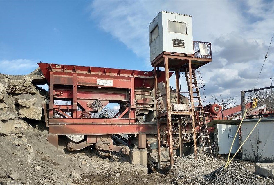 Used Pioneer VR 5260 Crusher and Screening Plant on a rocky site with a small white building on stilts to the right.