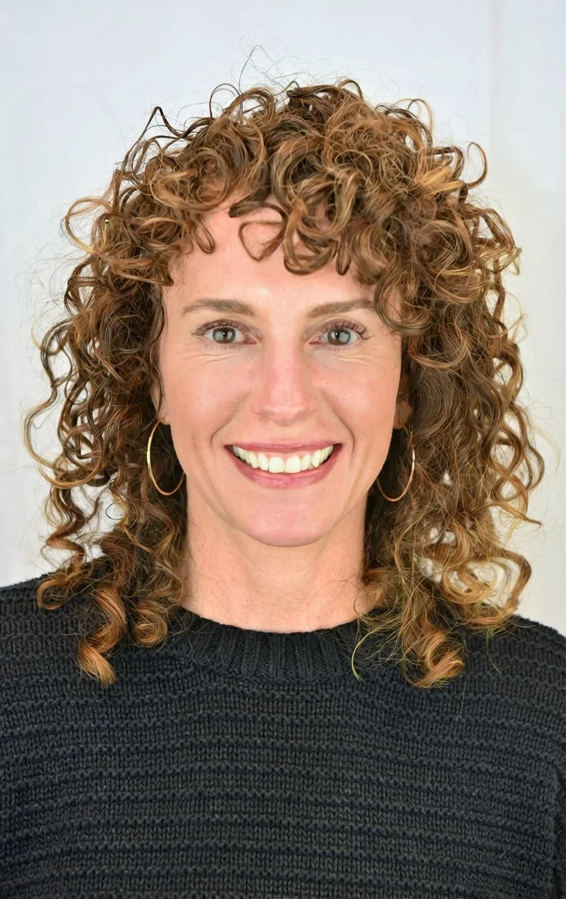 A picture of a white woman with long brown curly hair and hoop earrings