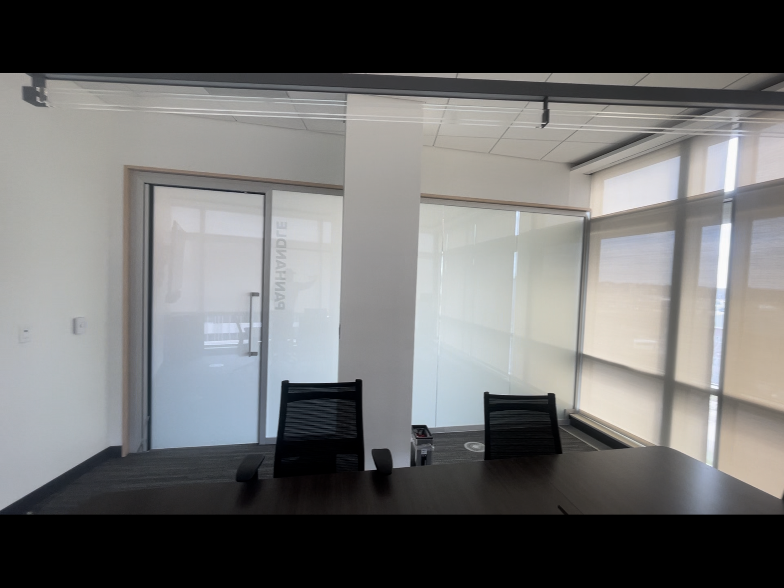 Empty modern conference room with glass walls, black chairs, and large windows with blinds. Smart Film 