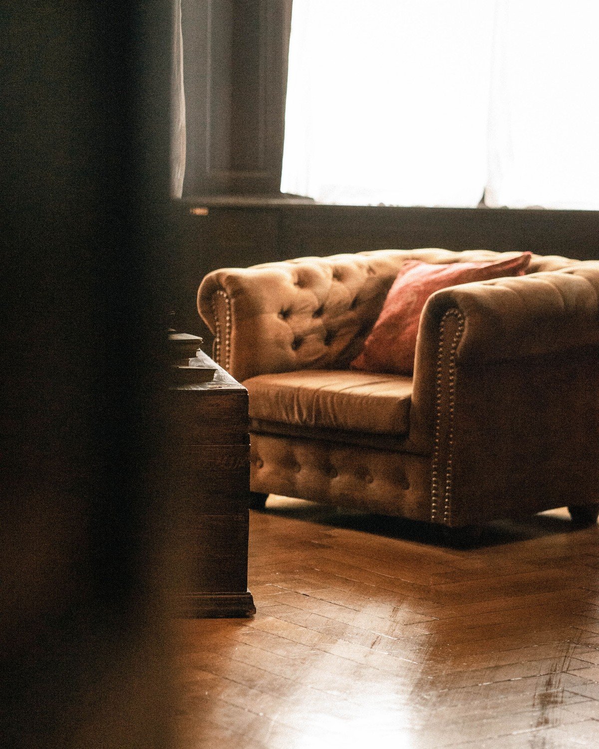 Warm, softly lit sitting room with a tufted couch and wood floors — the kind of calm space a social anxiety group meets in.