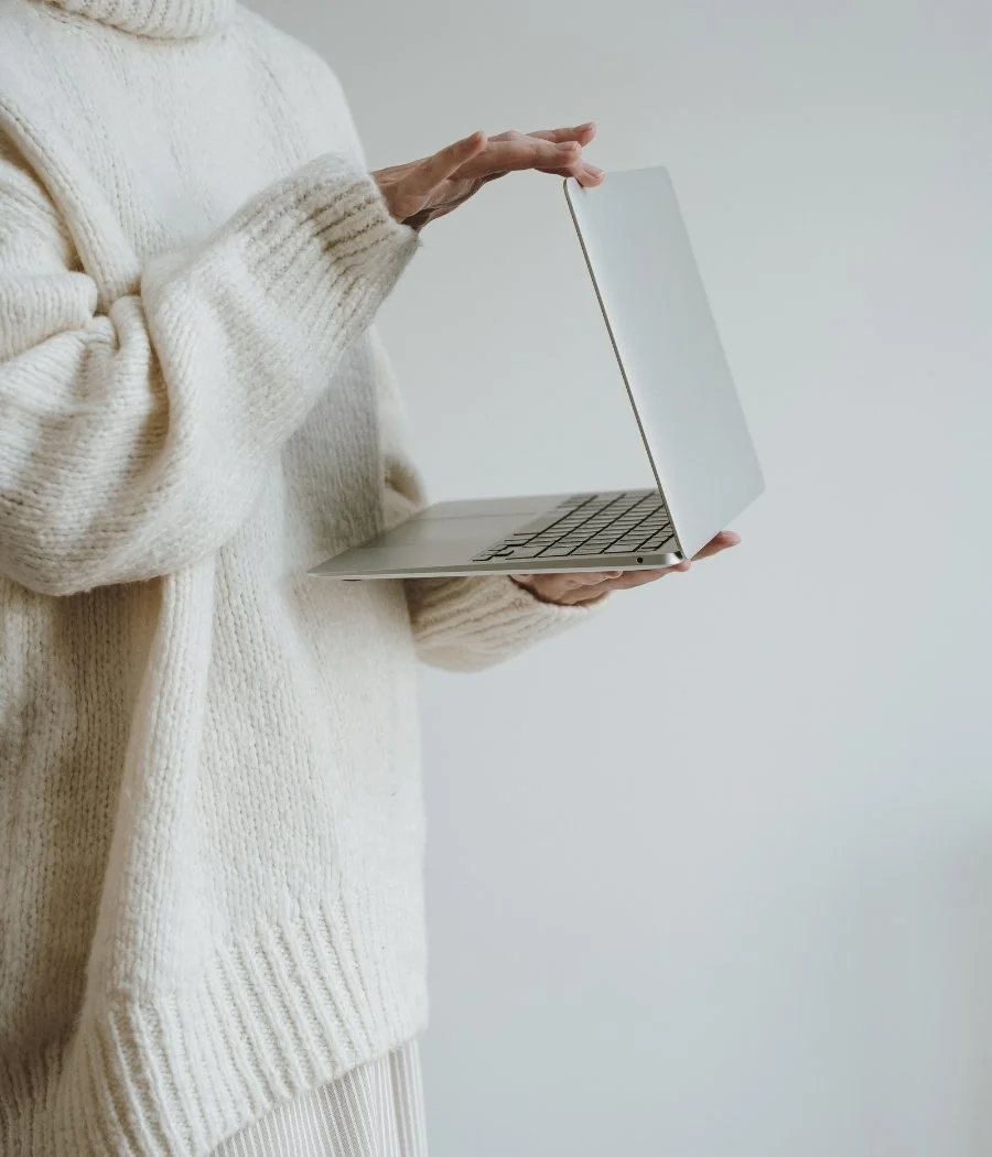 Esthetician holding a laptop to access done-for-you email marketing templates from The Glow Sis Email Club