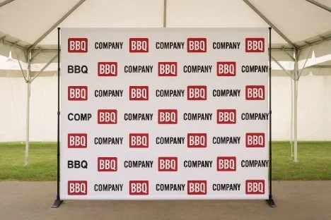 Event backdrop with repeating logos of BBQ, COMPANY, and black text on a white background inside a tent.
