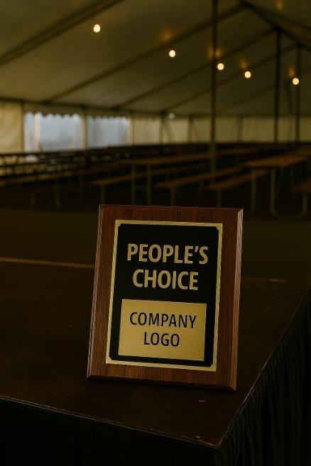 A sign on a table in a large event tent that says "People's Choice" with space for a company logo, with empty seating in the background.