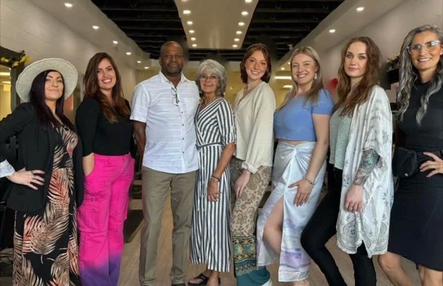 Group of beautiful women and one handsome well-dressed man in the hair salon presenting their team of professional hair stylists, extensionists, image hair design in Okotoks.