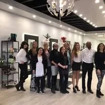 Group of eight women standing together in a modern indoor setting.