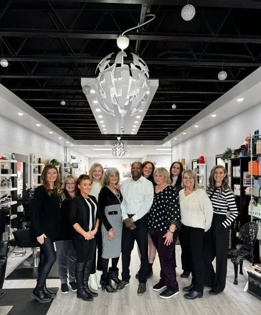 Group of women and one man standing together inside a modern retail store, smiling for a photo.