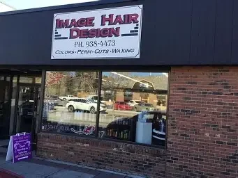 Sign for Image Hair Design with contact number and services listed, outside view of the salon with windows and reflected cars.