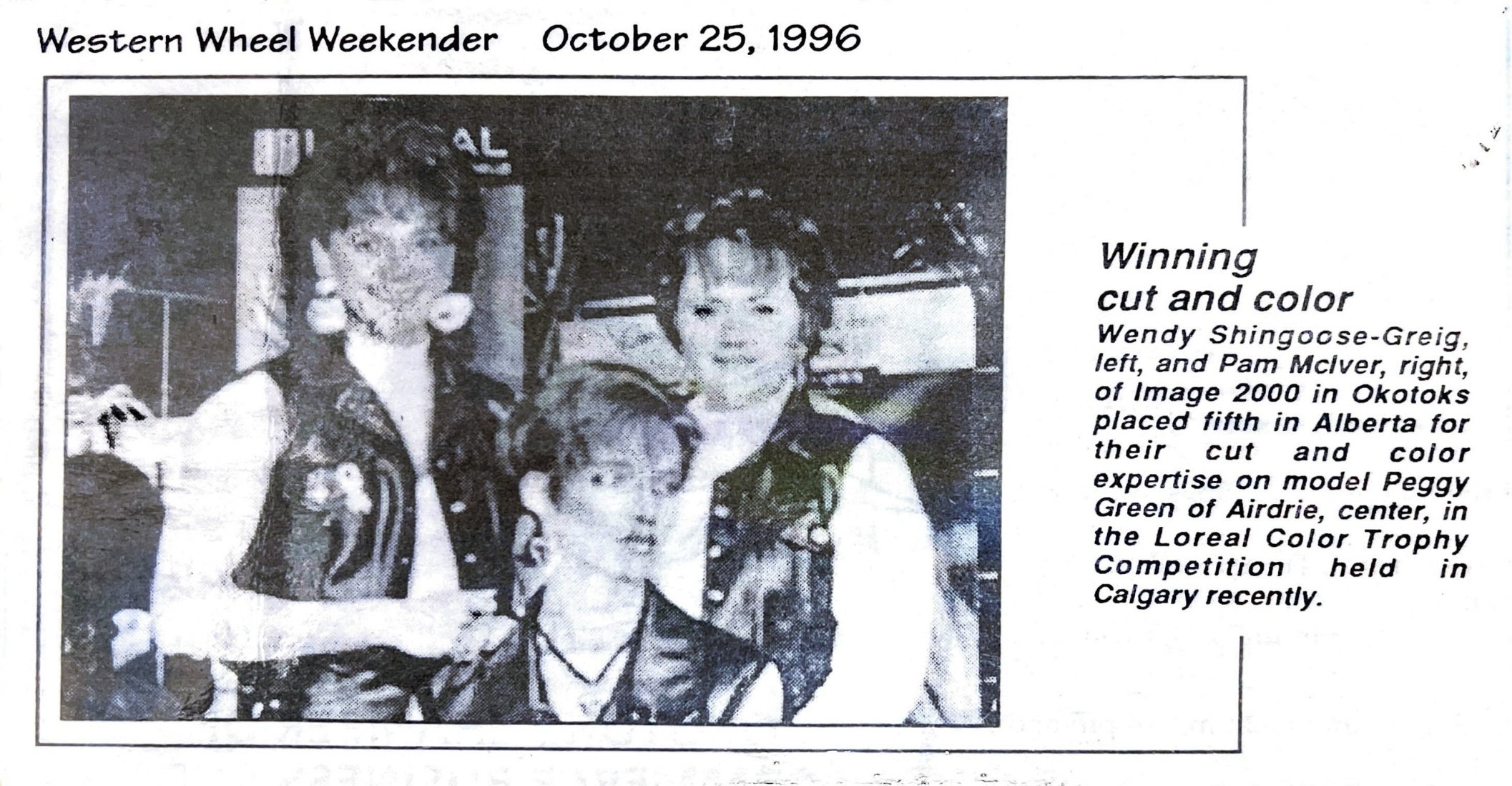 Black and white photo of three individuals at an award event, a woman standing on the left, a young girl seated in the center, and a woman standing on the right. The background shows partial signage and indoor setting.