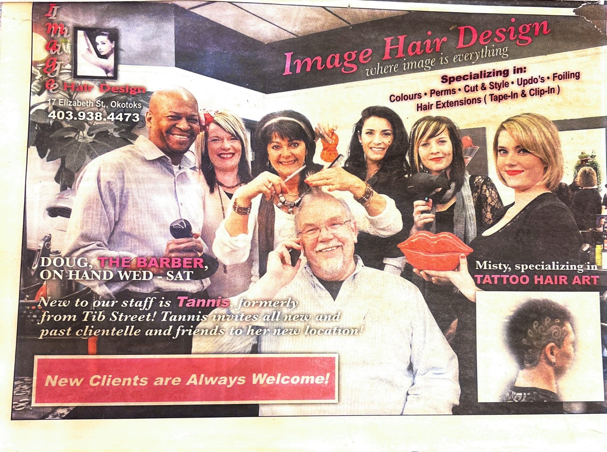 A group of seven people in a hair salon or barbershop, some holding hair styling tools or accessories, and engaging in conversation. The background has signage for a hair design business, highlighting services like coloring, perming, cutting, styling, and hair extensions. The image also features a small inset photo of a woman with styled hair and a decorative lips prop held by a woman.