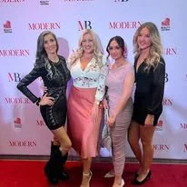 Four women standing together on a red carpet at a fashion event, with a background displaying the logos 'Modern' and 'MB.' Models, Stylists, Beauty, Women, men, Fashion