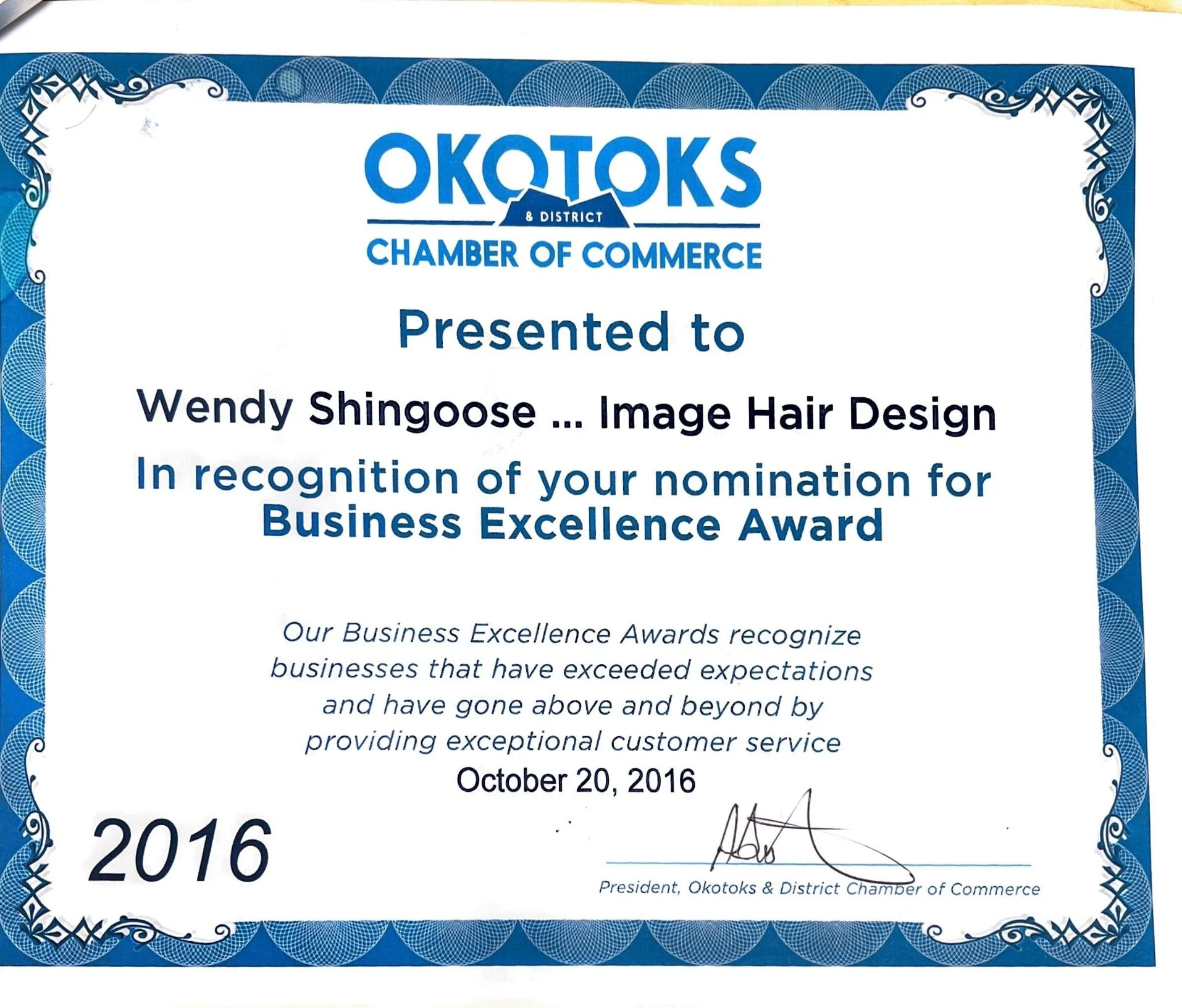 Certificate of recognition awarded to Wendy Shingoose by Okotoks & District Chamber of Commerce for Business Excellence Award, dated October 20, 2016, with a blue decorative border and signature at the bottom right.