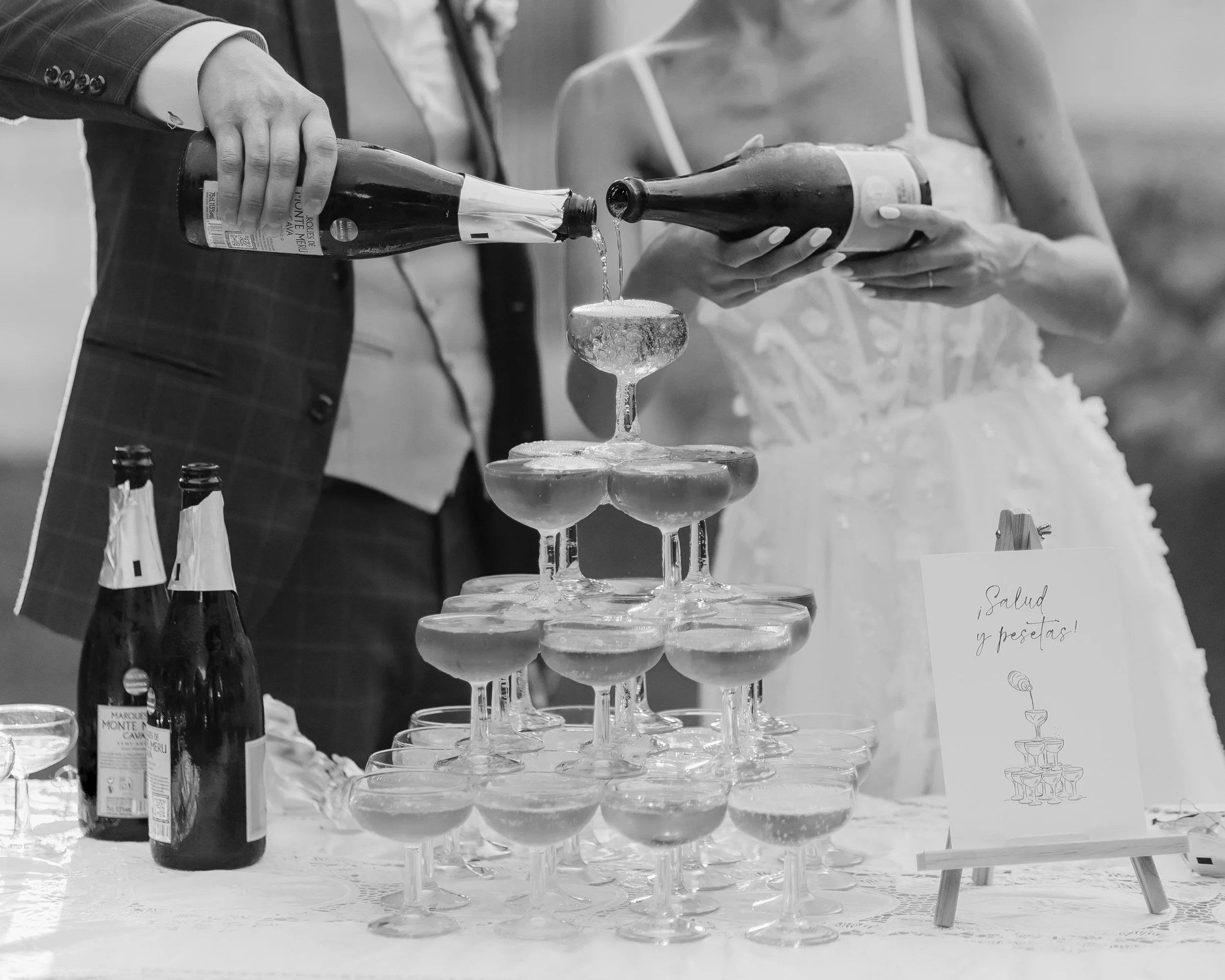 A man and woman pouring champagne into a tower of glasses at a celebration event.
