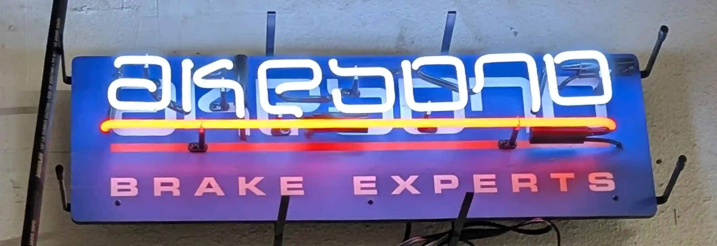 Neon sign for Brake Experts with both English and Thai text, illuminated in blue, red, pink, and yellow colors.