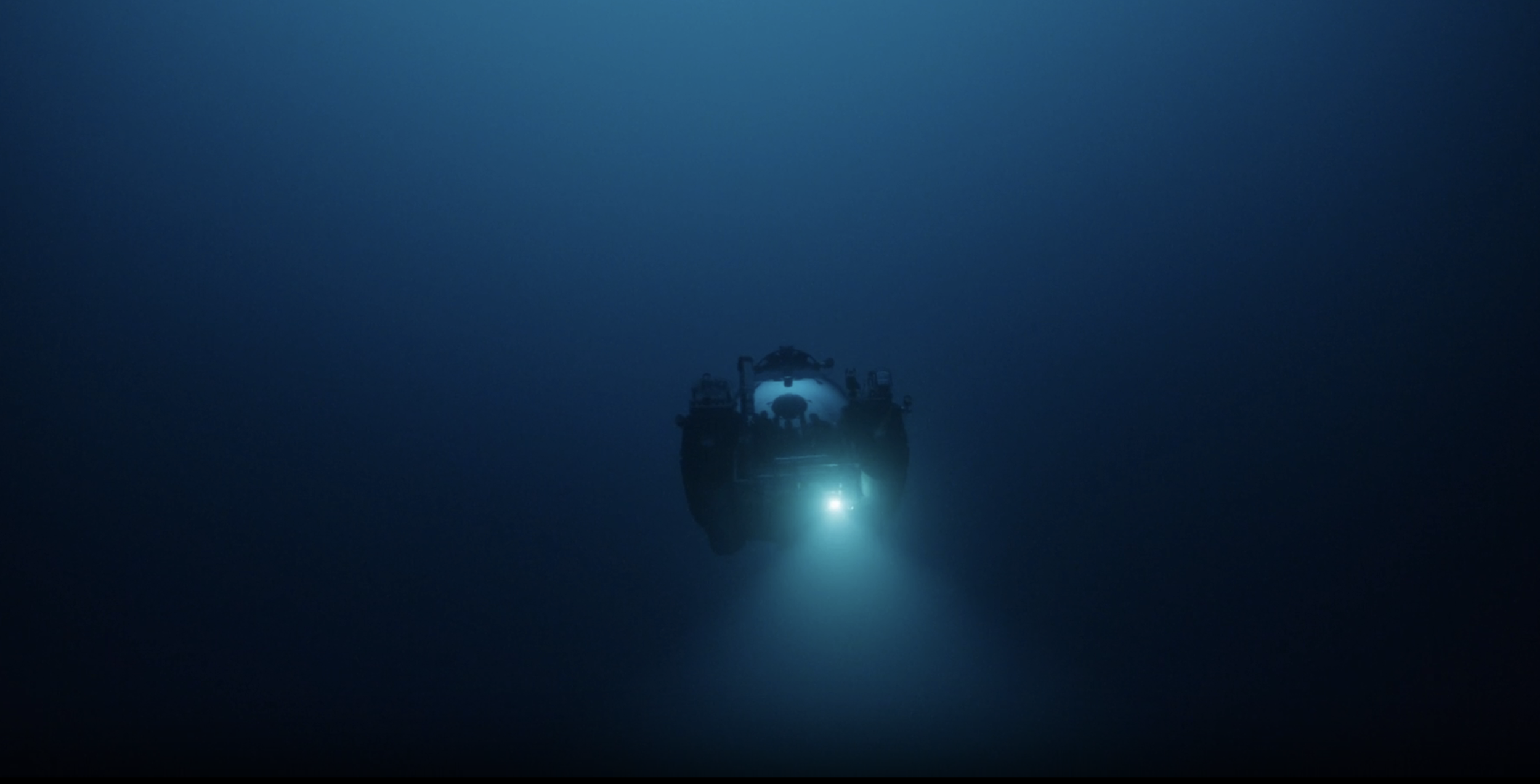 A deep-sea submersible with external lights navigating in the dark ocean depths.