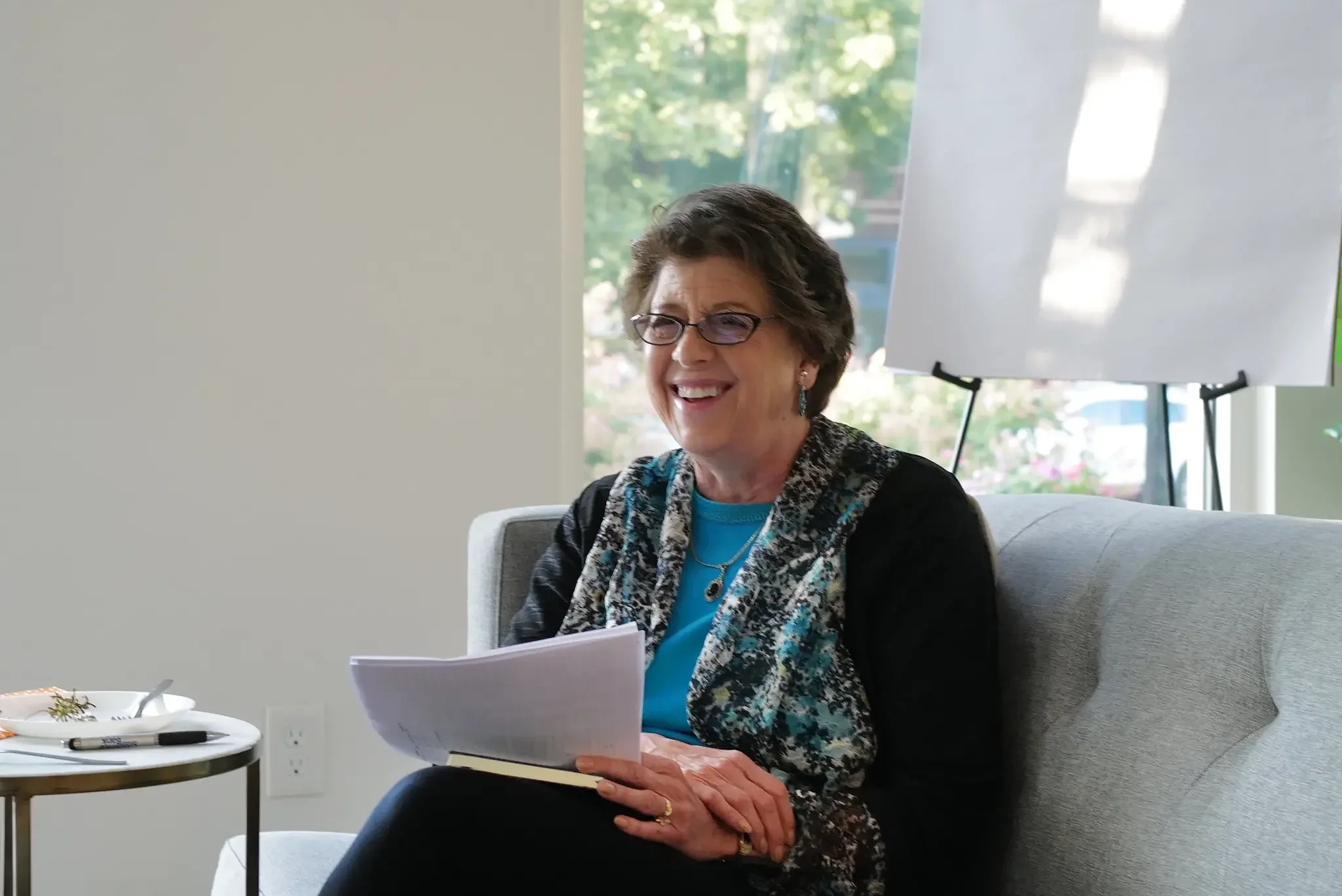 A woman holding papers sitting at an event.