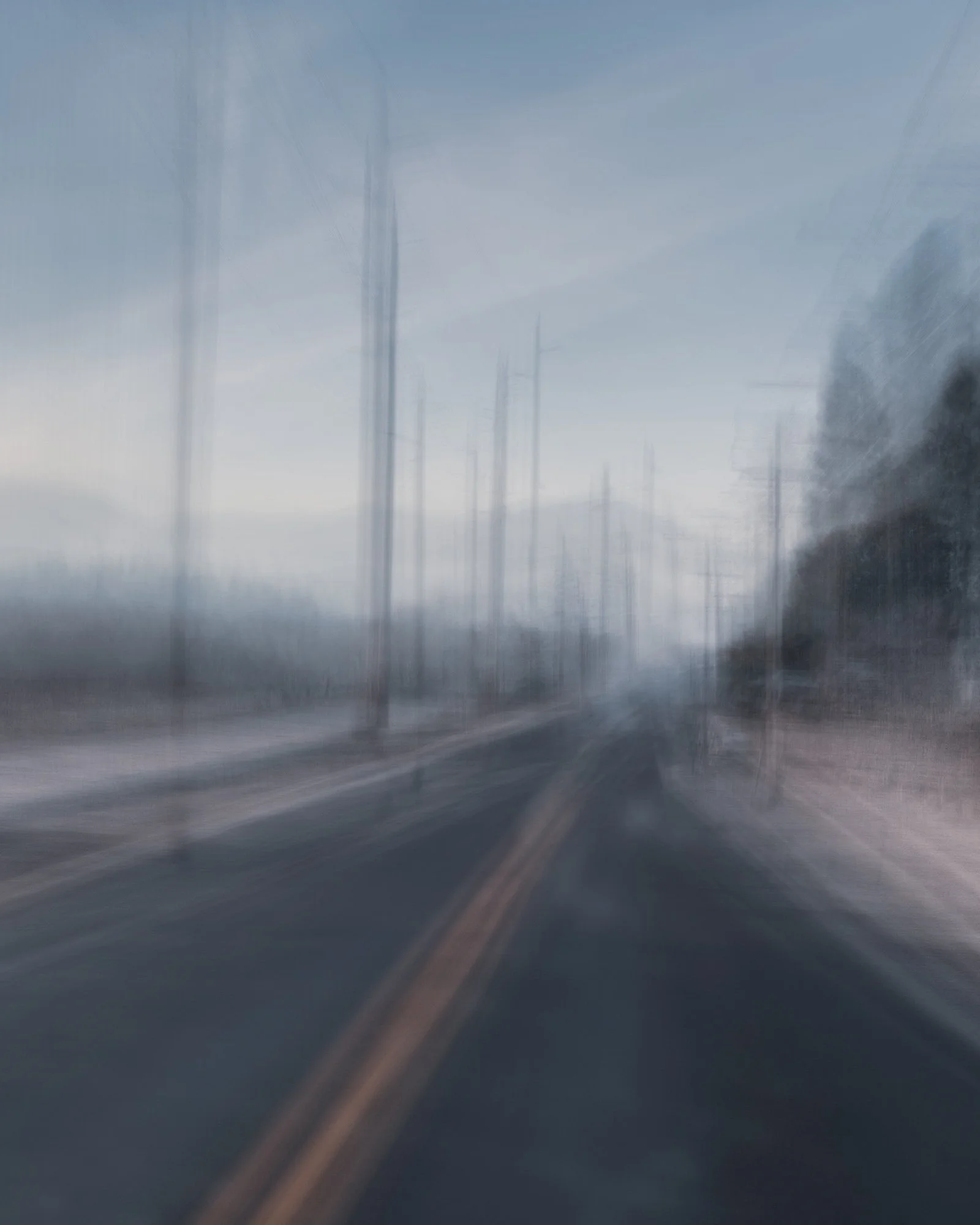 Blurred view of a rural road with power lines and trees on the side.