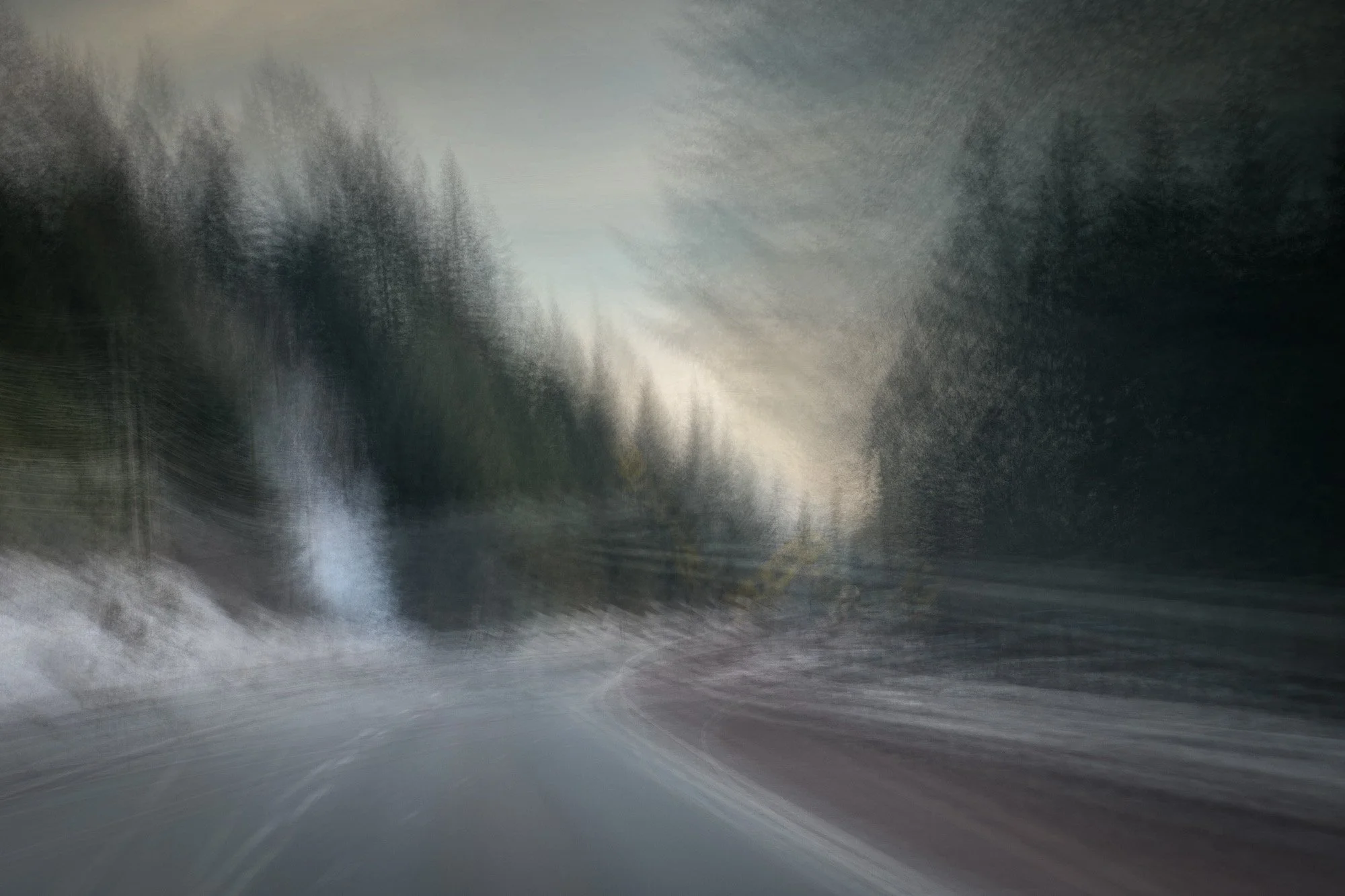 Blurry view of a forested road with trees on both sides, captured during a rainstorm or misty weather.