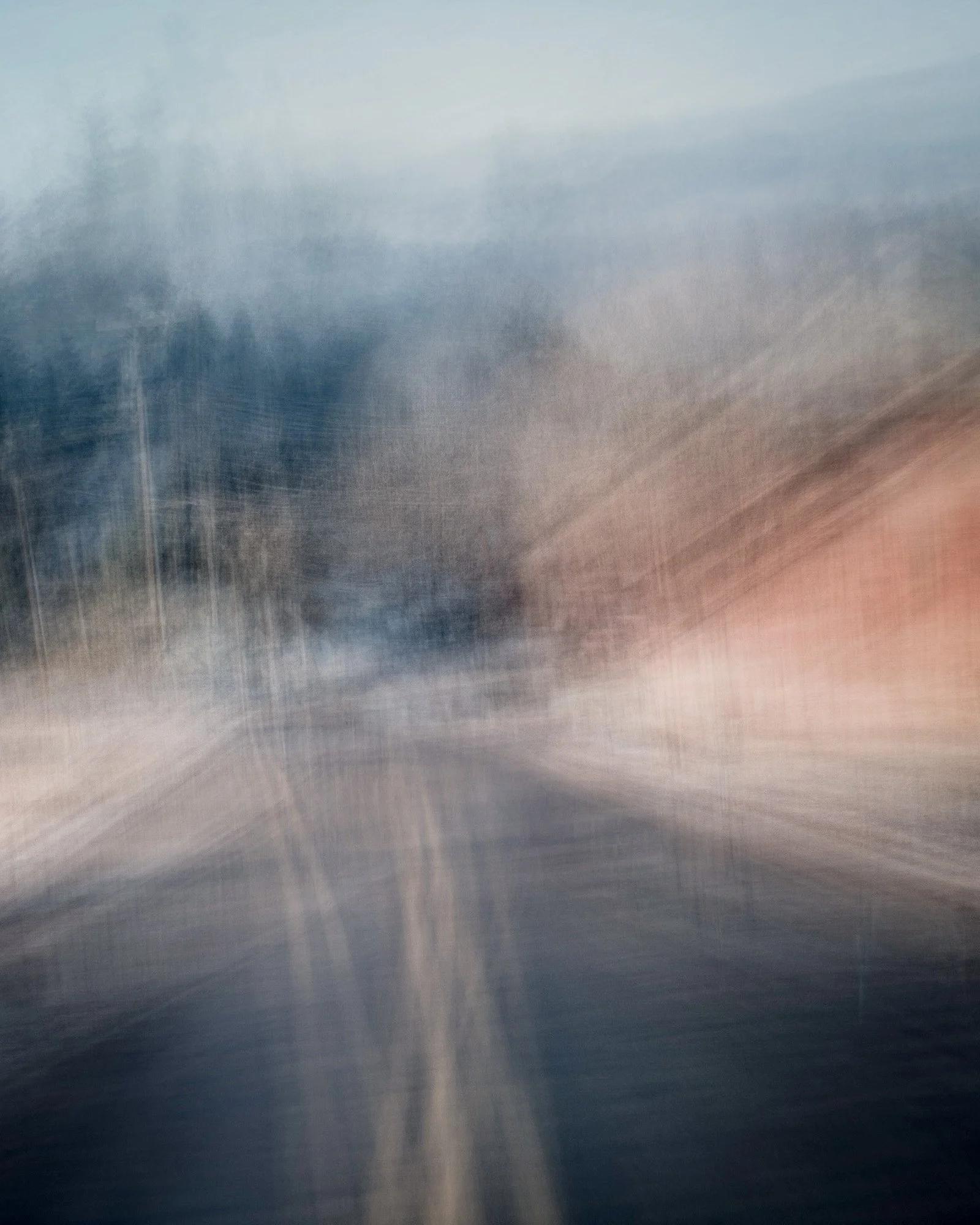 Blurred image of a street scene with buildings, trees, and cloudy sky, moving quickly as if from a moving vehicle.