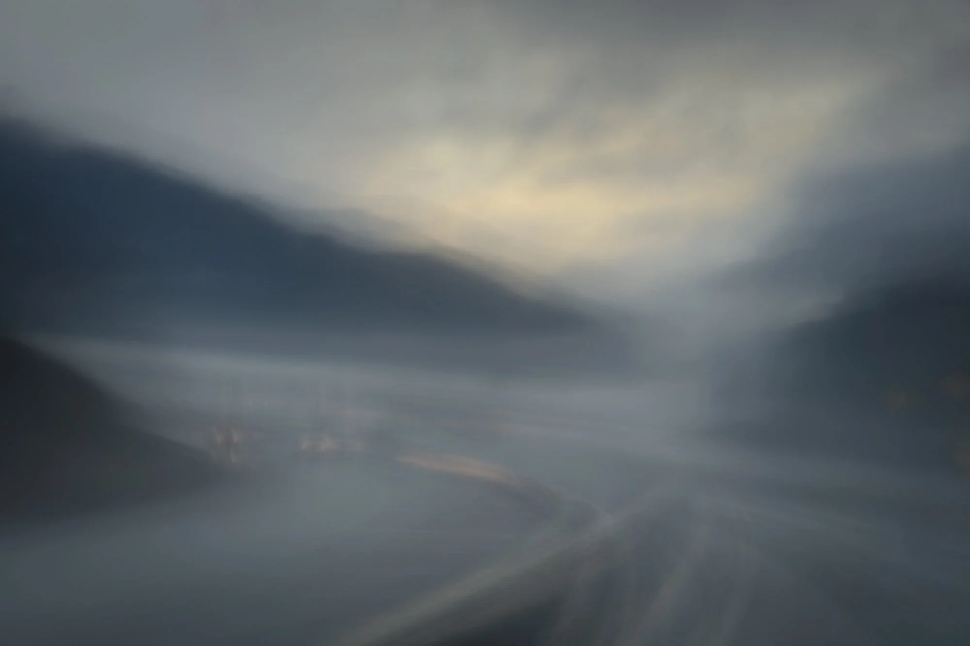 A blurred view of a highway with a cloudy sky overhead, suggesting motion or a long exposure shot.