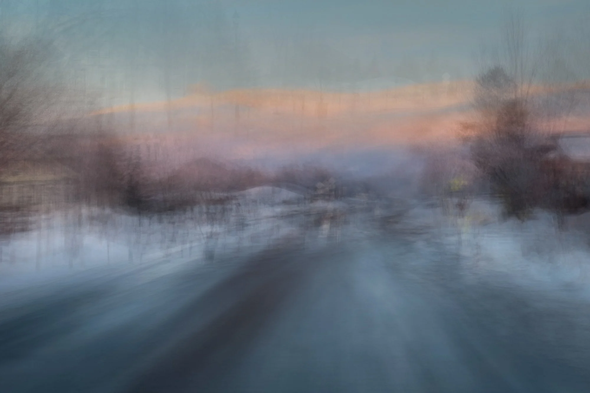 Abstract blurred landscape of trees and water with pink and blue sky.