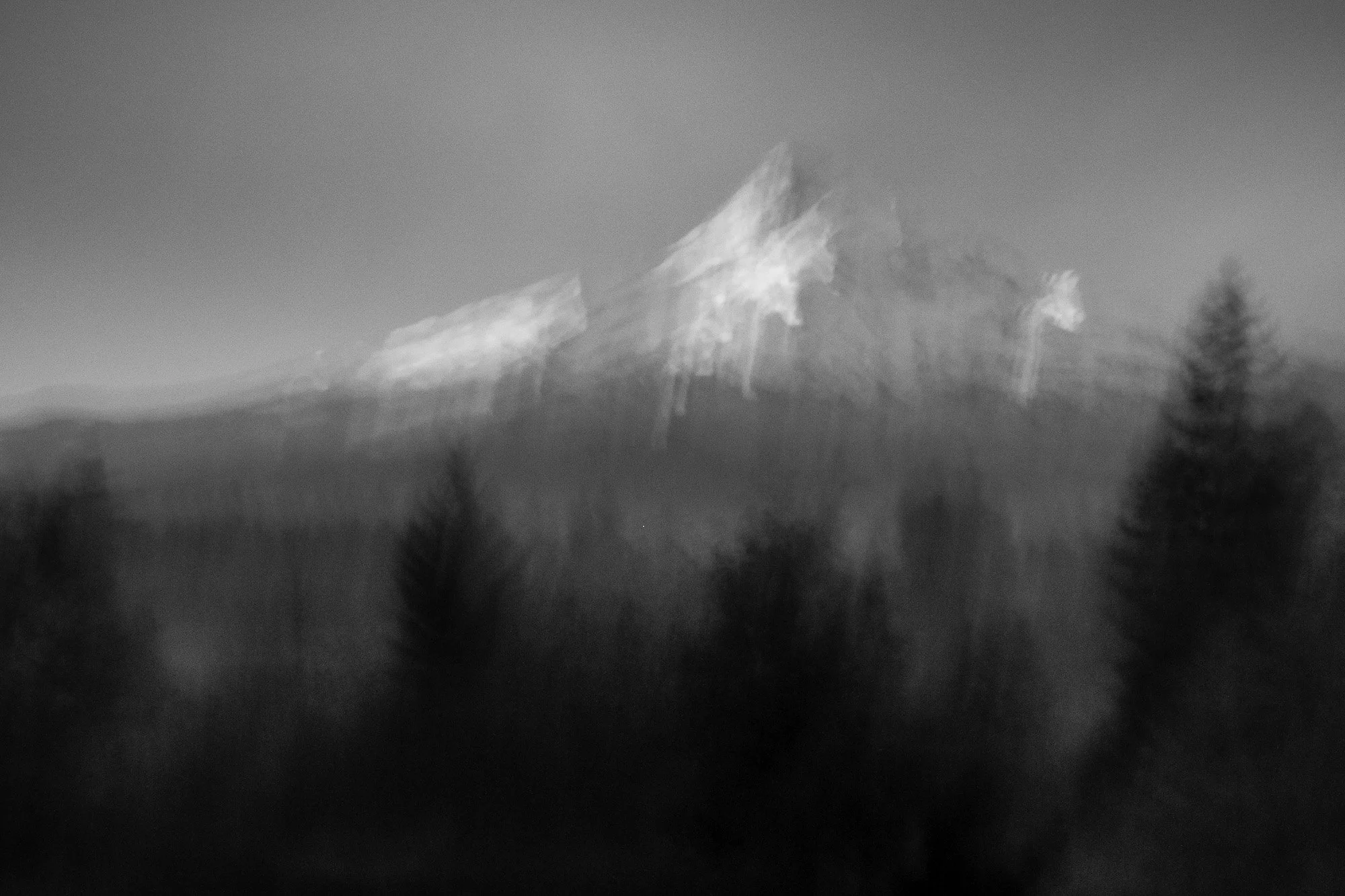 Black and white photograph of a mountain with trees in foreground.
