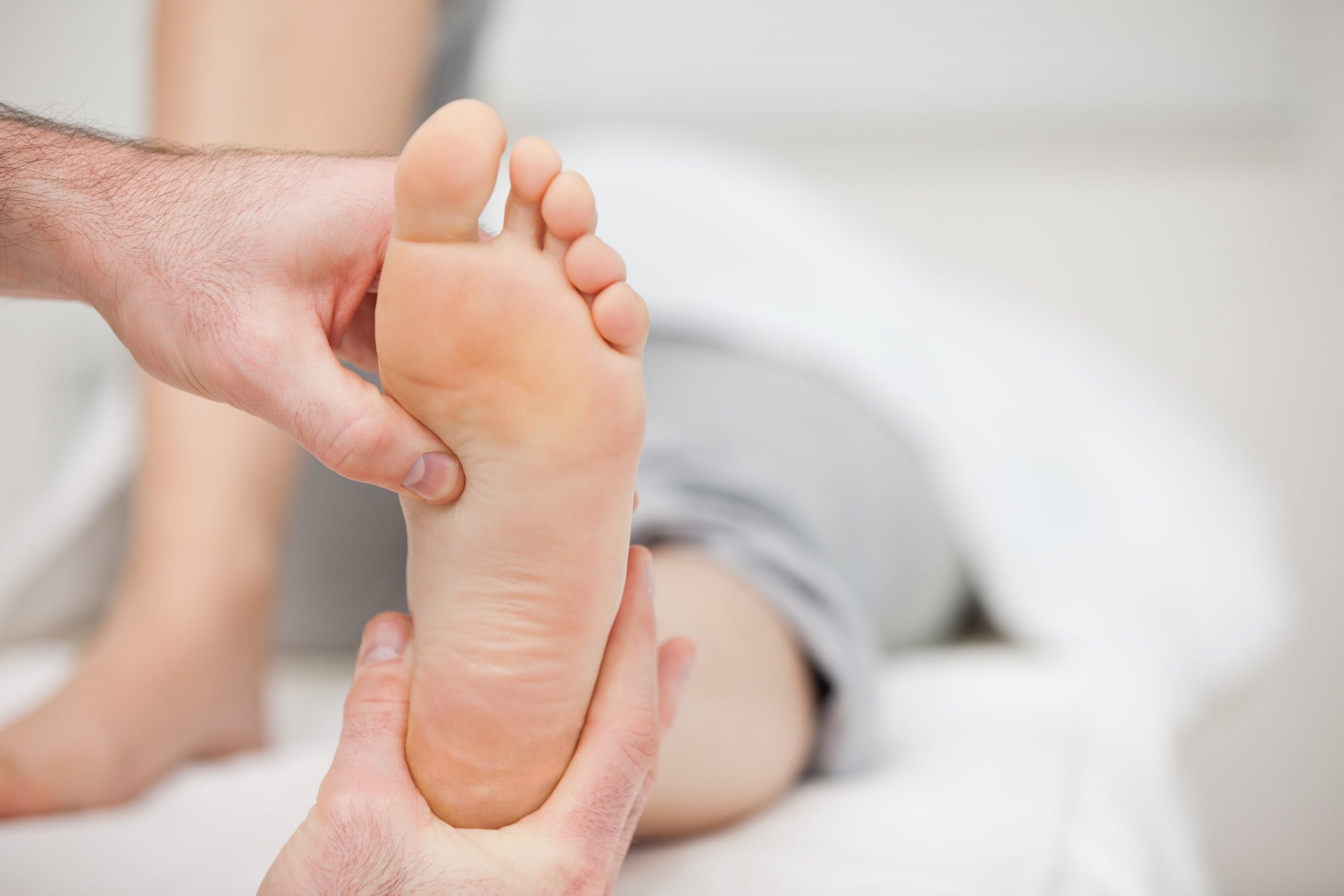 A person holding a foot during a medical check, with the foot prominently in focus.