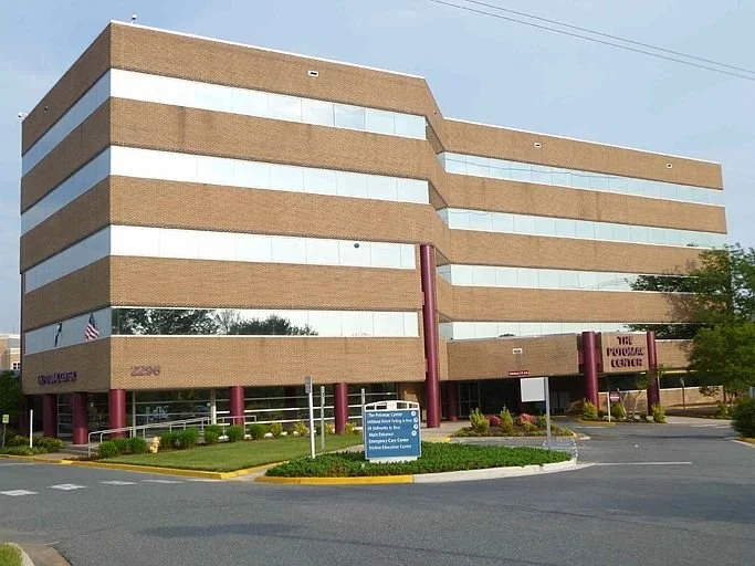 Office building with beige brick facade, large tinted windows, and purple supports at the entrance, labeled The Workforce Center.