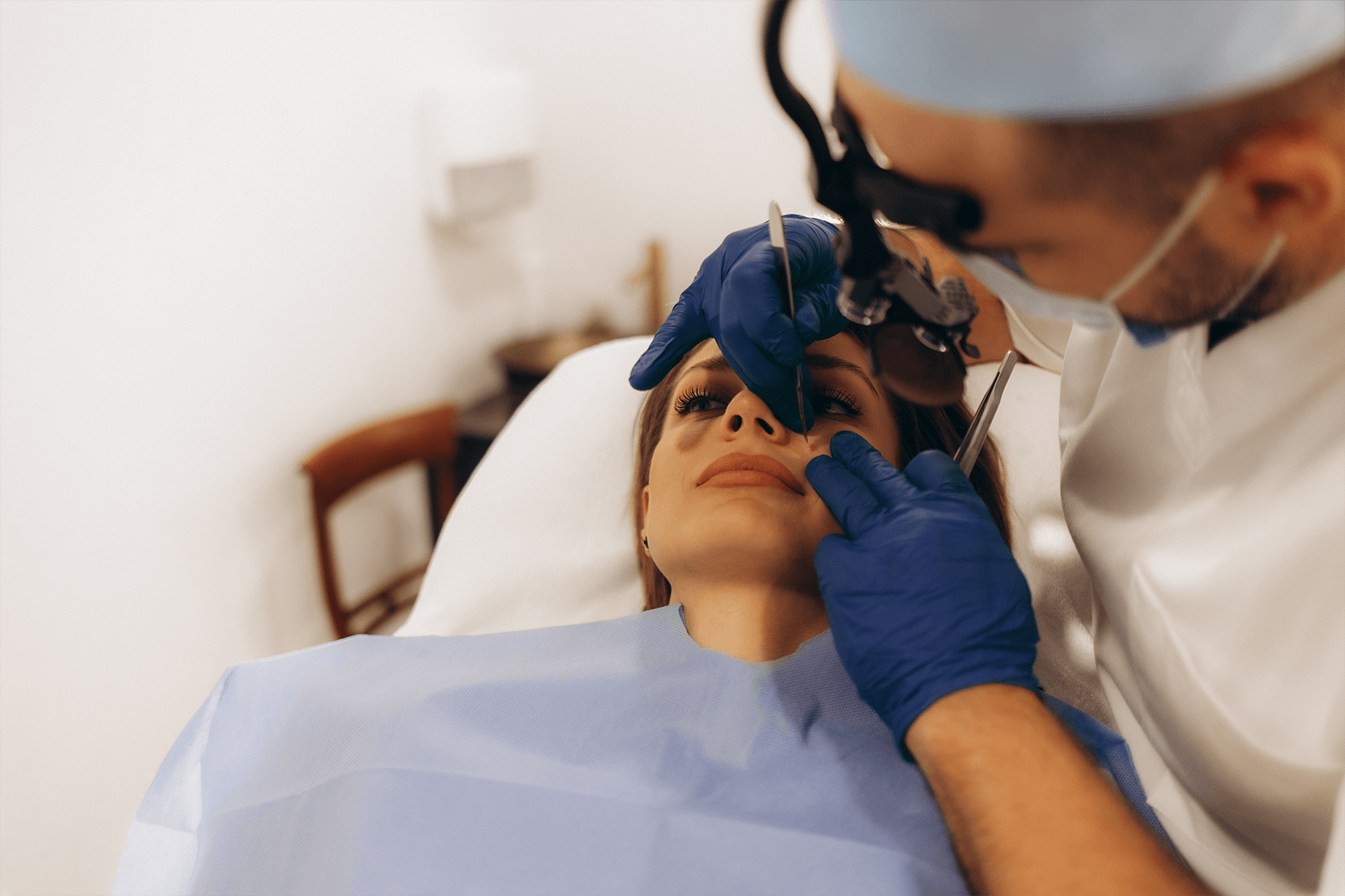 A woman receiving a cosmetic procedure on her lips from a dermatologist in a clinical setting.