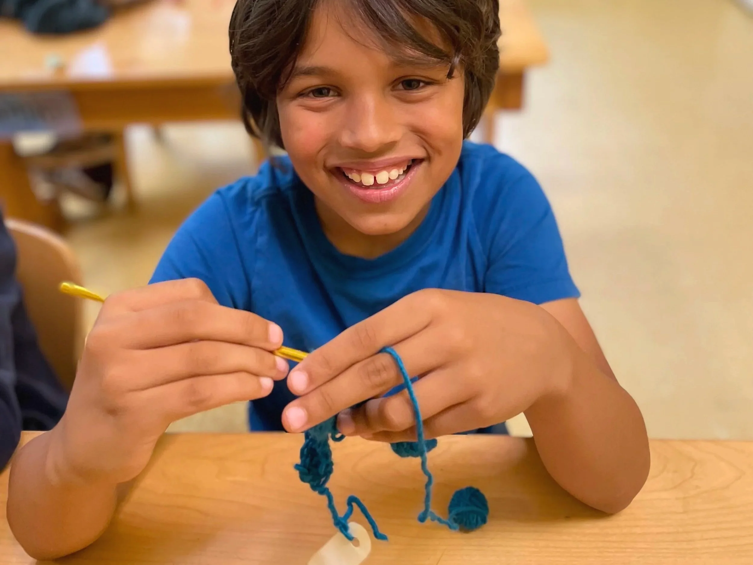 Child smiling and knitting