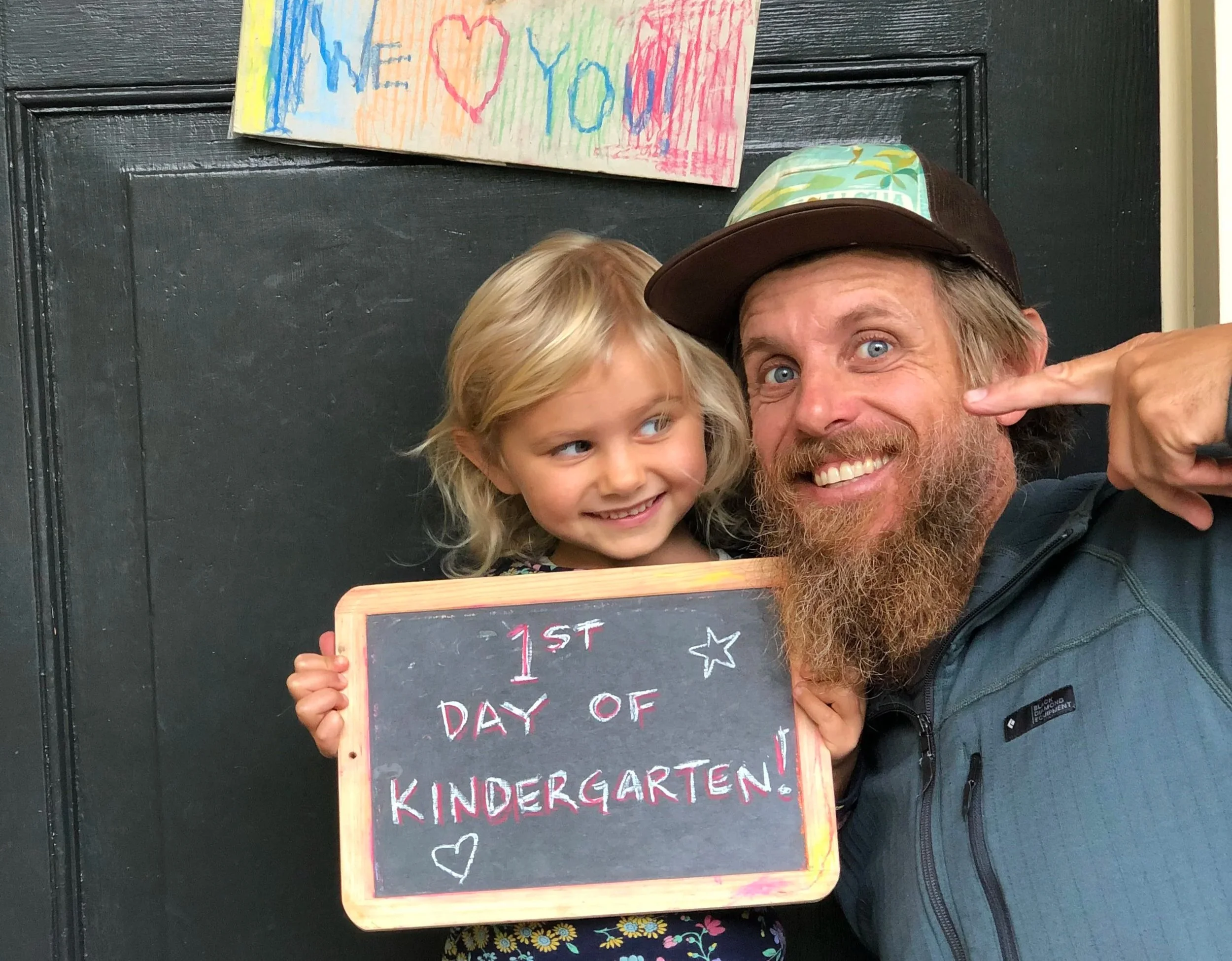Father and daughter with "First Day of Kindergarten" sign