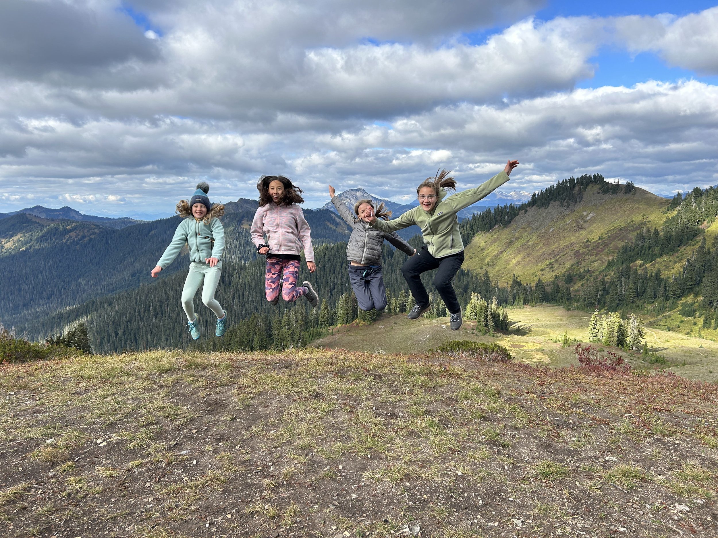 Children leaping on a mountain hillside