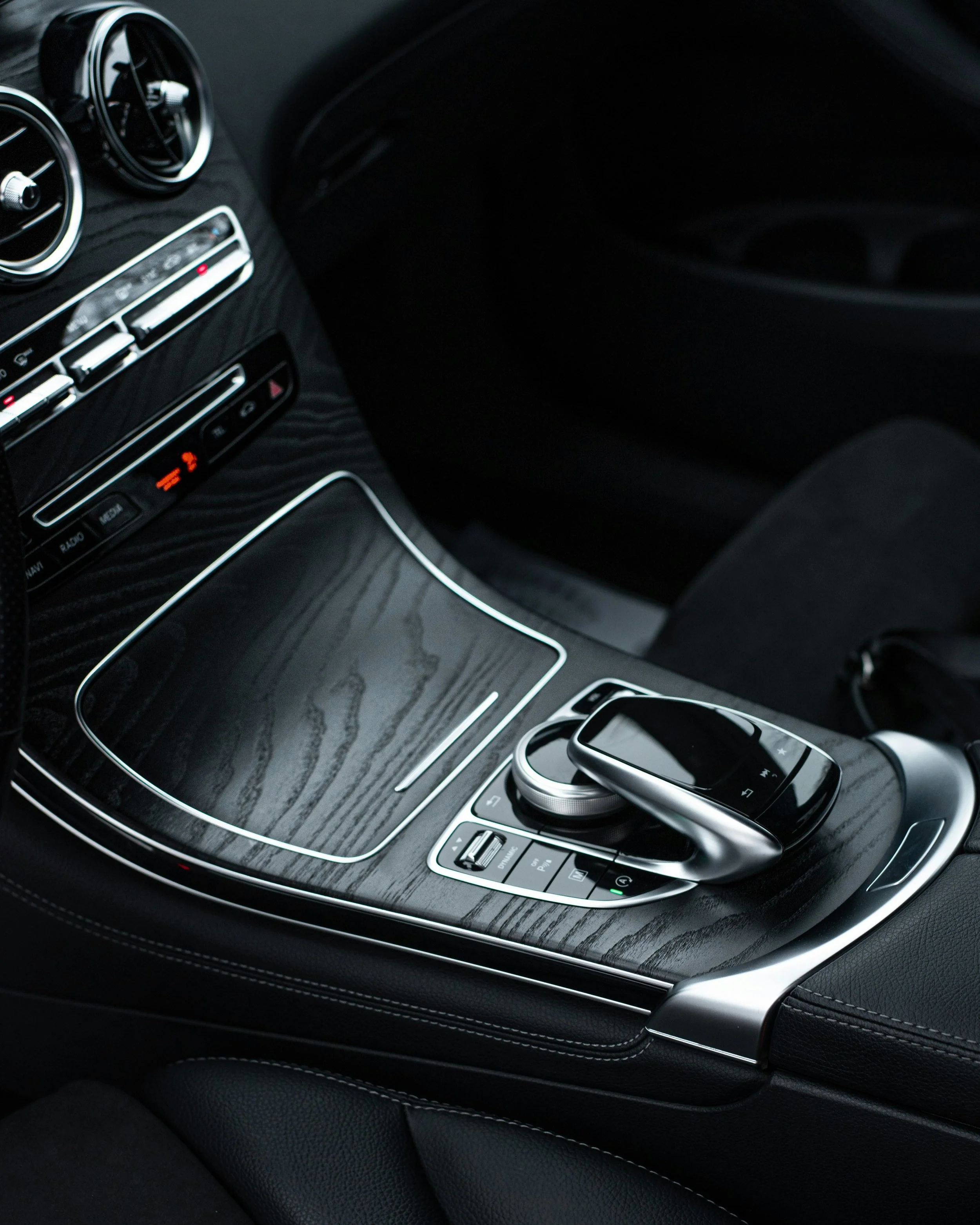 A matte black Ford truck parked in front of a modern house with a brick and beige exterior under a clear blue sky.