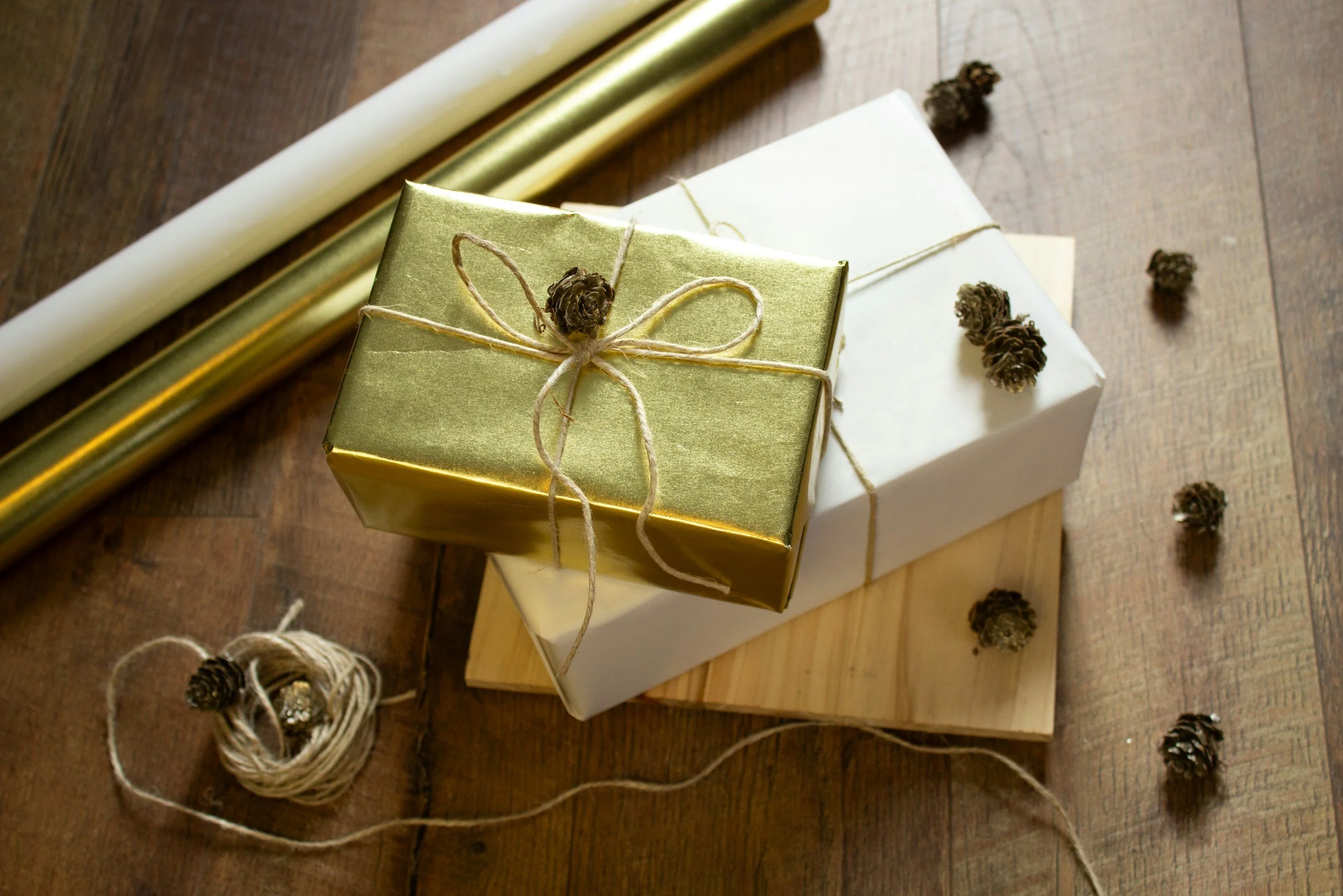 Stack of 3 wrapped gifts- one gold, one white and the bottom a flat yellow gift