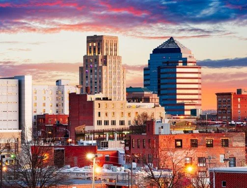 Cityscape at sunset with modern skyscrapers and older brick buildings.