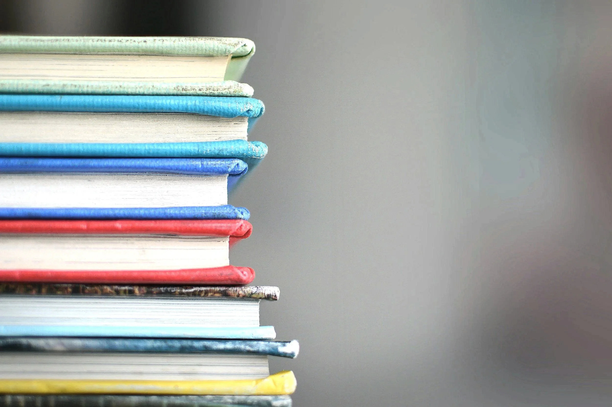 Stack of colourful books with worn covers on the left side of the image.