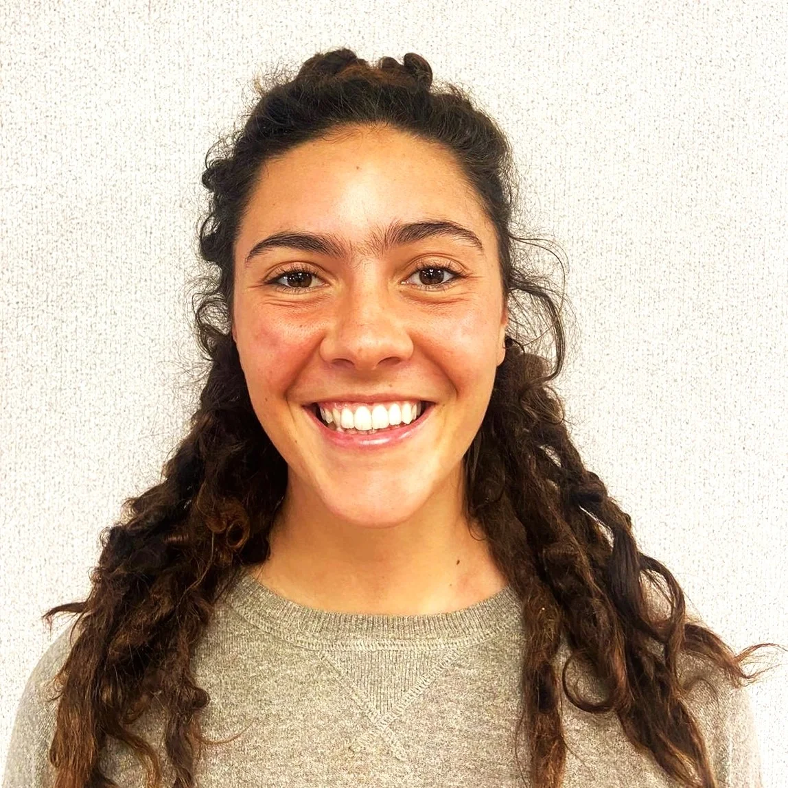 A man with dark wavy hair, glasses, and a beard looks content and thoughtful.