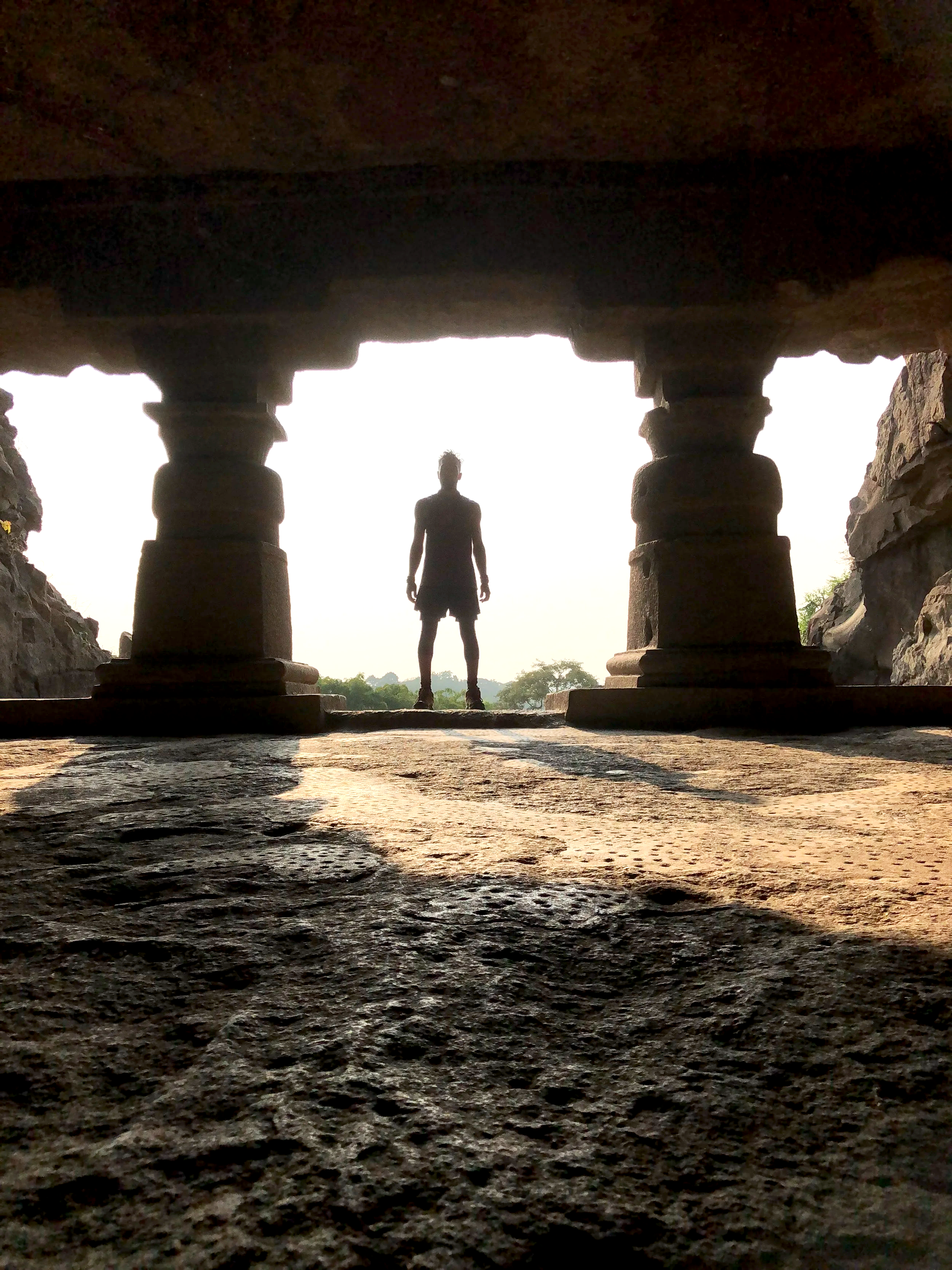 A historic cemetery with stone mausoleums and vaults, surrounded by trees and a gravel pathway.