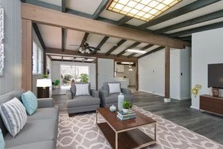 Living room with gray sofa, armchair, wooden coffee table, patterned rug, and large windows in a modern home.