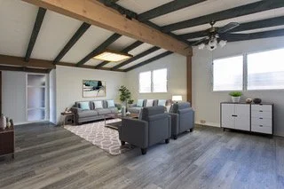 Living room with gray furniture, a patterned area rug, large windows, and modern decor.