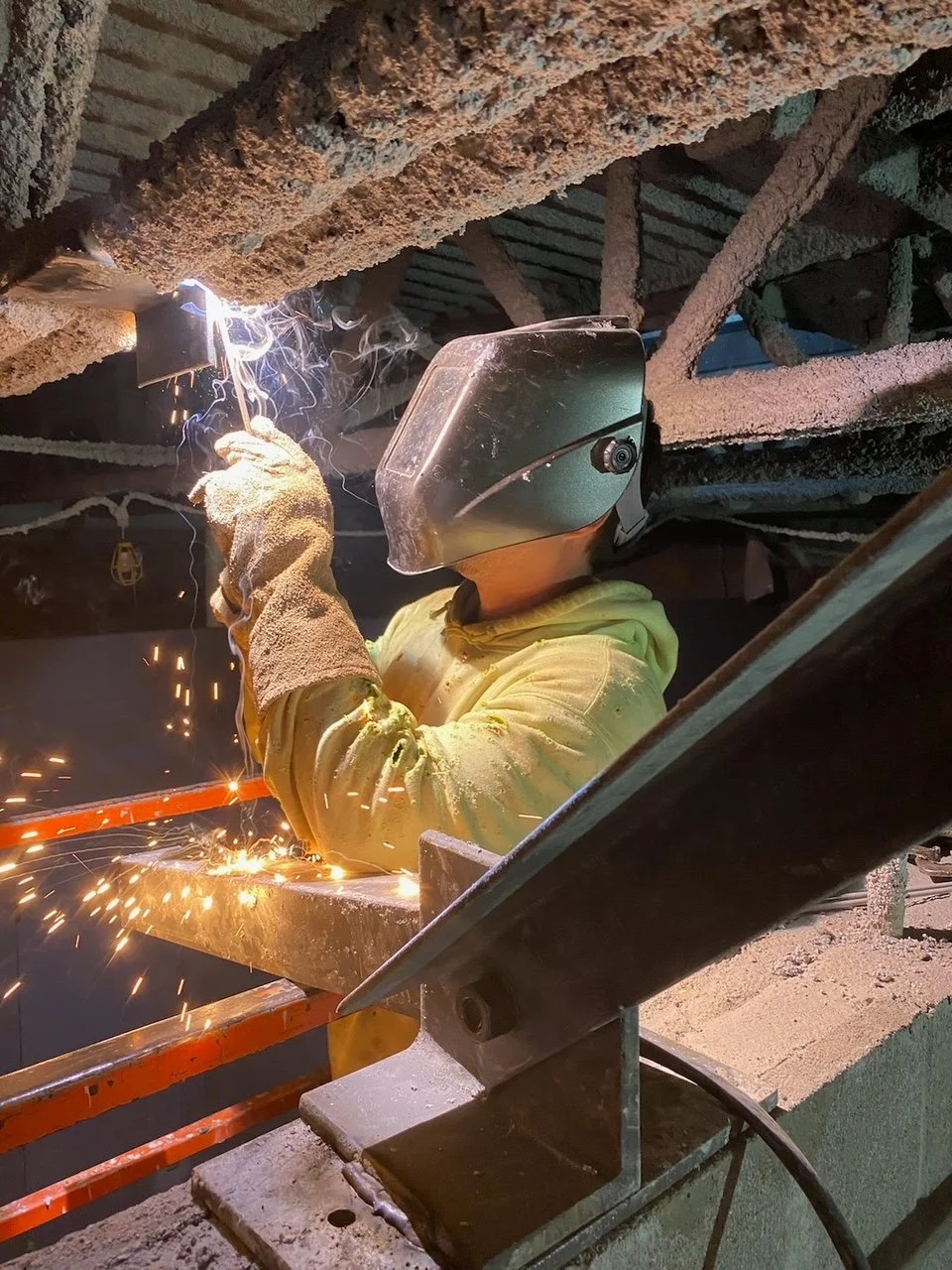 welder performing overhead welding on structure
