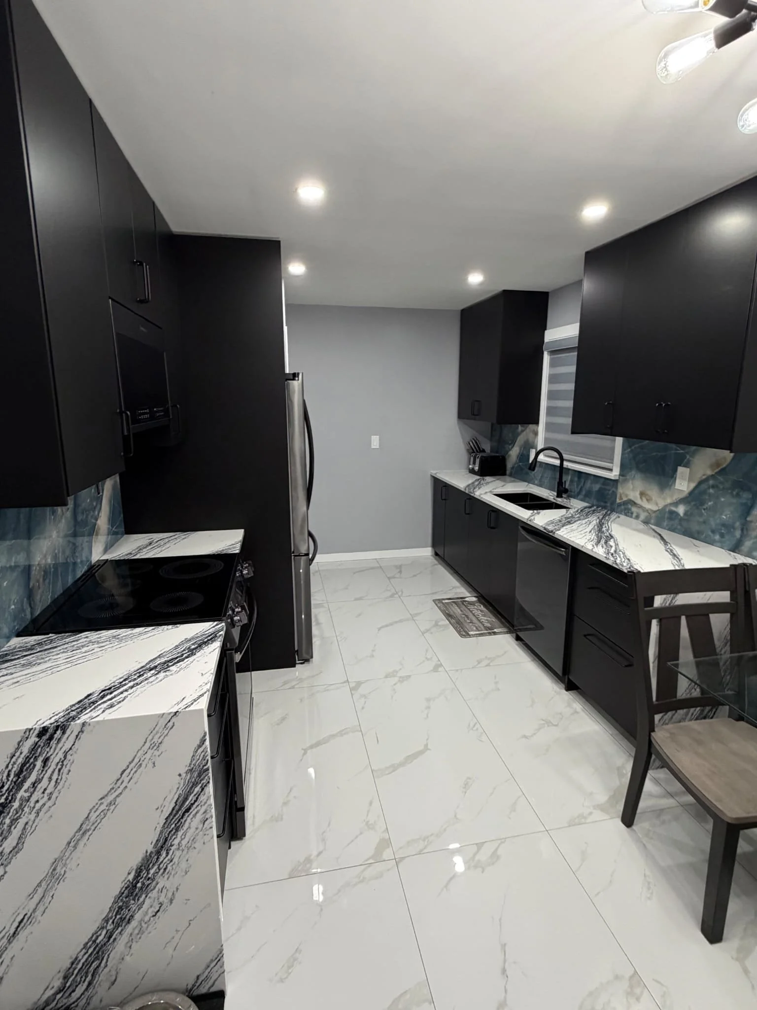 Kitchen renovation with black cabinets and marble tile flooring in Thorold