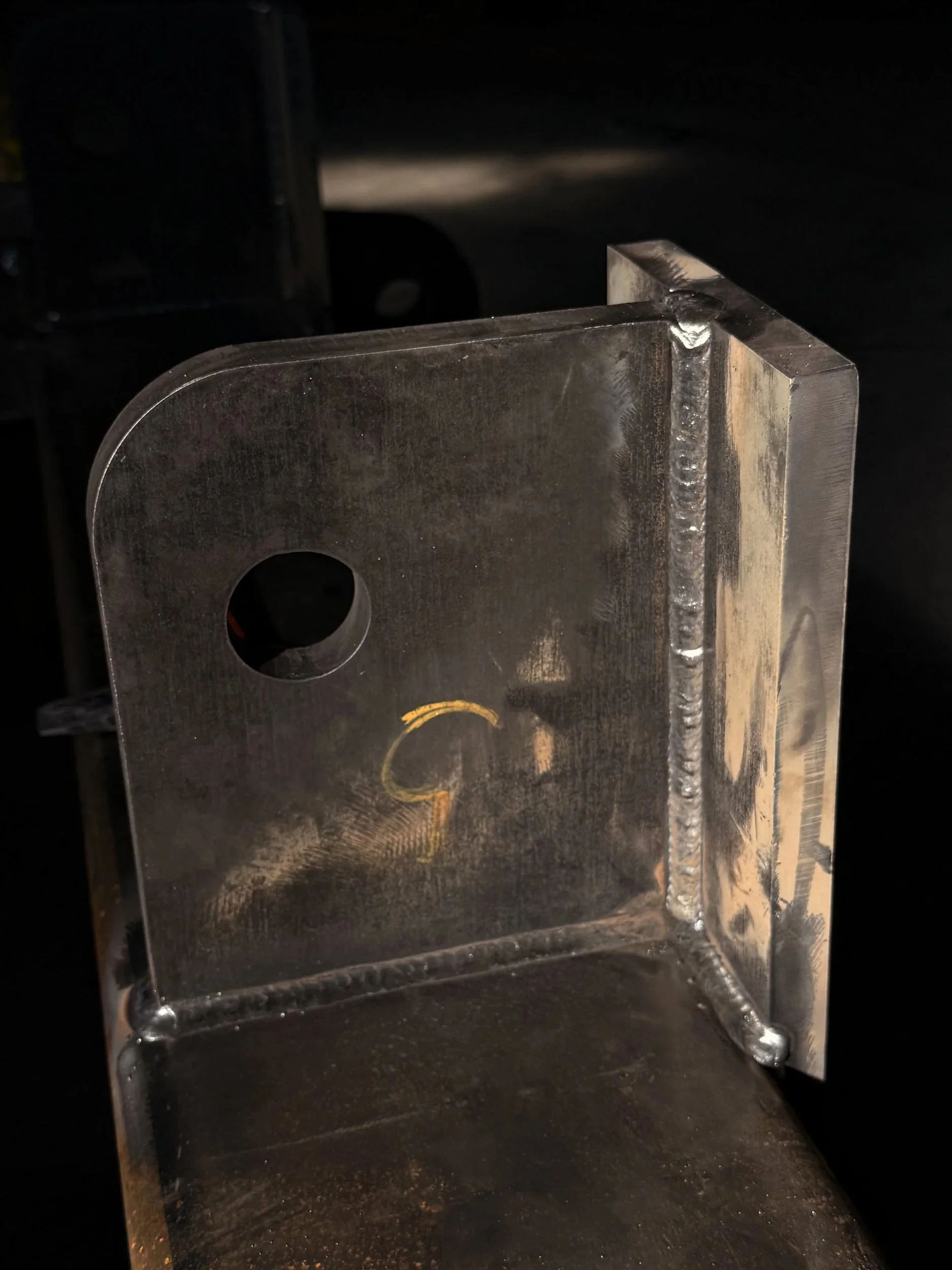 Close-up of a metal box with a circular hole cut into the side and welding marks along the edges.