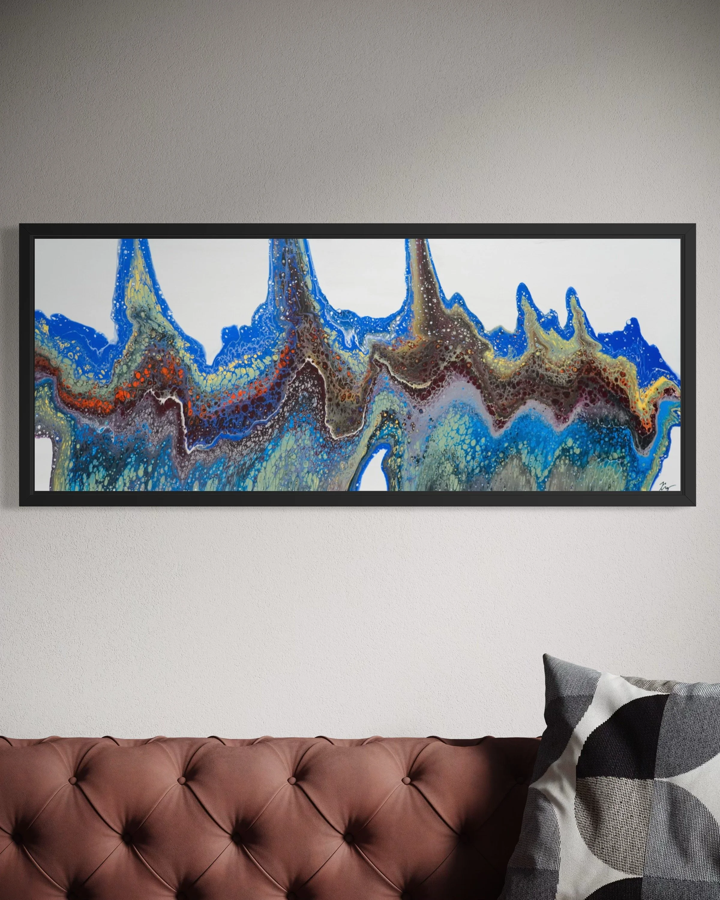 A colorful abstract painting with blue, yellow, brown, and white tones hanging over a brown tufted sofa with a black-and-white patterned throw pillow, on a light gray wall.