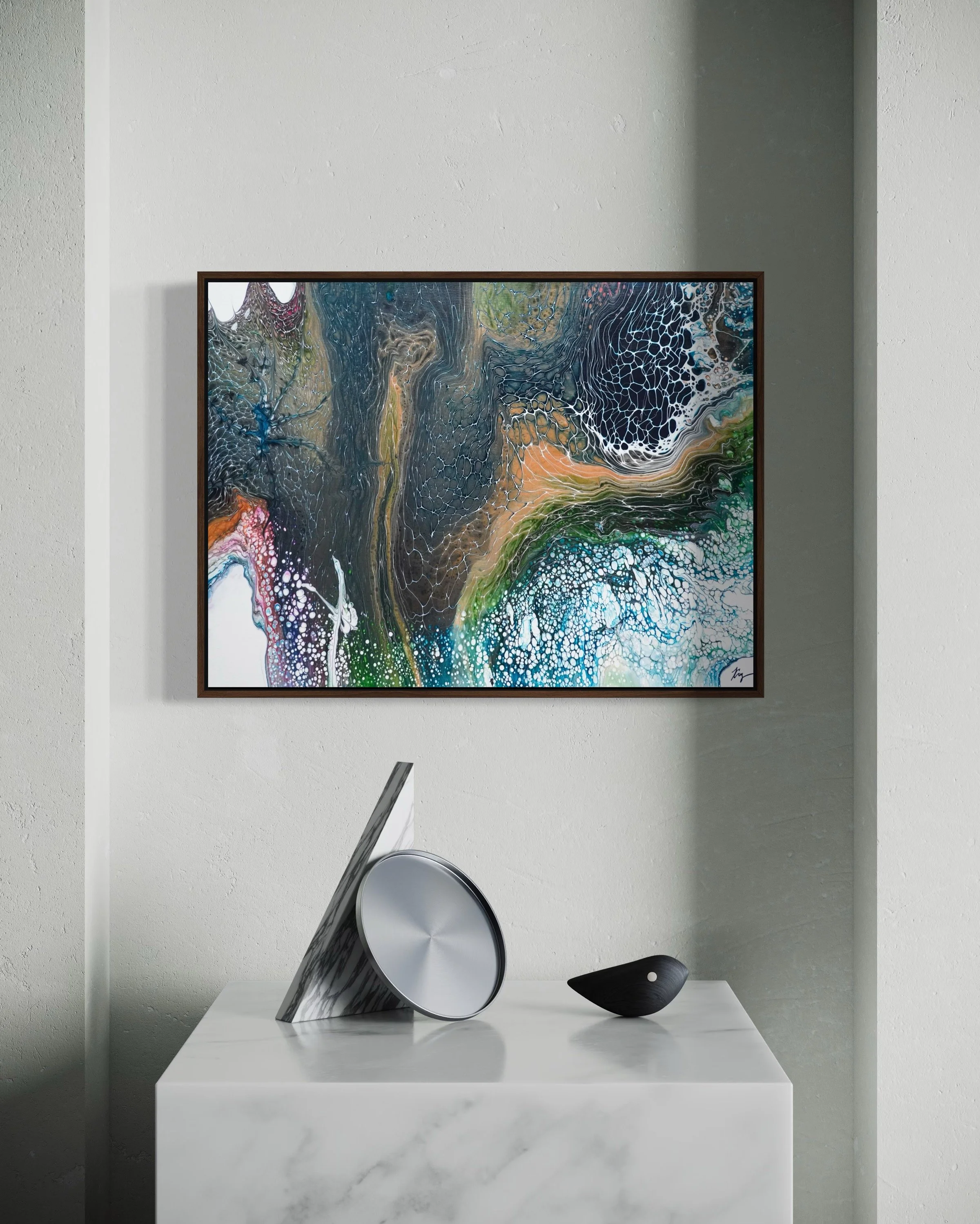 Abstract colorful painting hanging on a white wall above a white marble table with decorative objects.